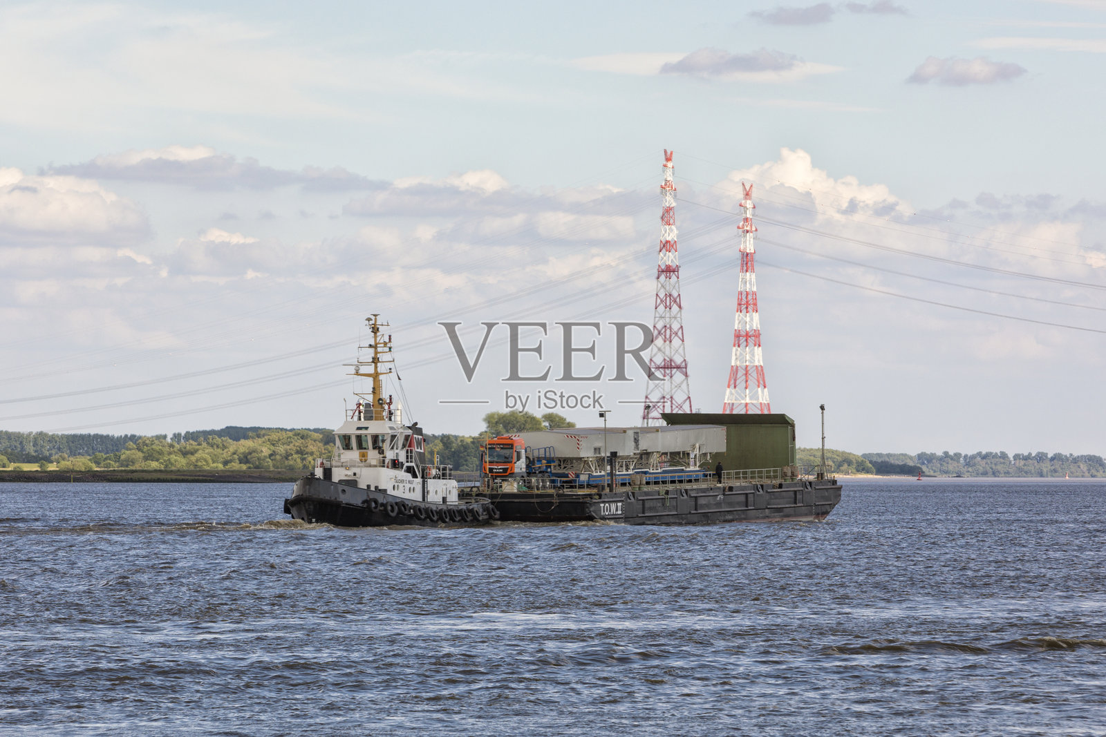 拖船推着装有重型货车的甲板货驳照片摄影图片