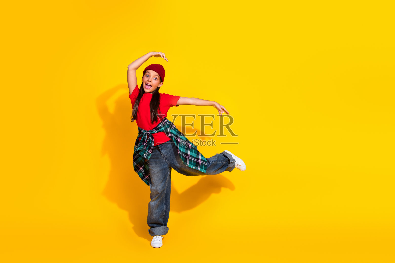活泼的女孩在充满活力的黄色背景下欢快地跳舞，穿着休闲的嬉皮风格，充满快乐的能量。照片摄影图片