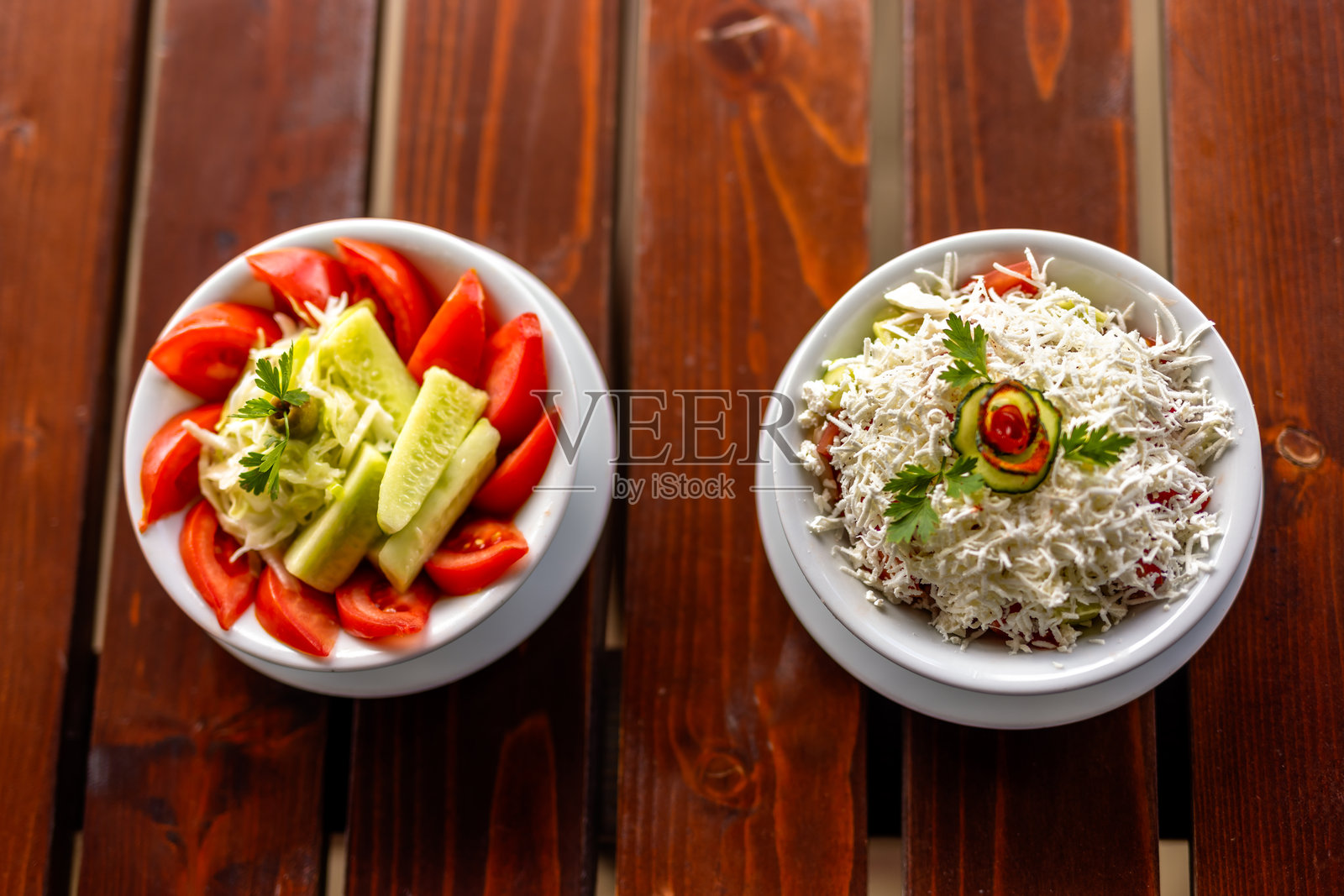 新鲜黄瓜和番茄沙拉盛在碗中，放在木桌上。照片摄影图片