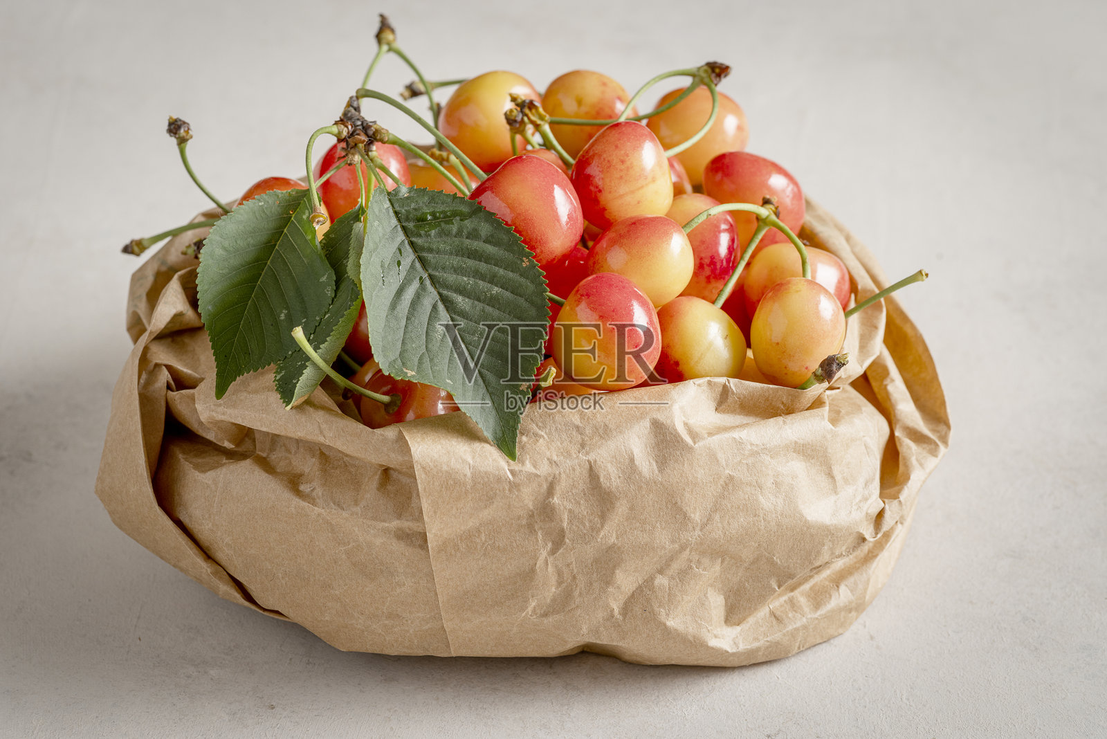 一袋“拿破仑”品种的樱桃，背景为浅色。照片摄影图片