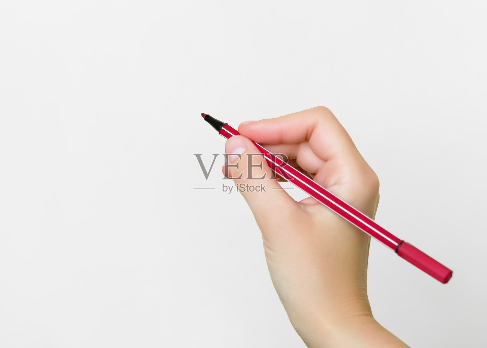 手握红色钢笔在白色背景上照片摄影图片