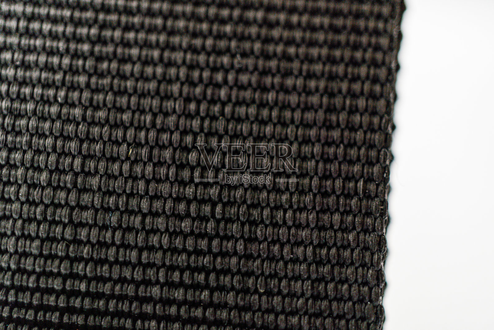 这张图片特写展示了一种高质量的深色面料，具有复杂的图案，突显其奢华的质感和耐用性。简单的白色背景衬托出面料独特的设计。照片摄影图片