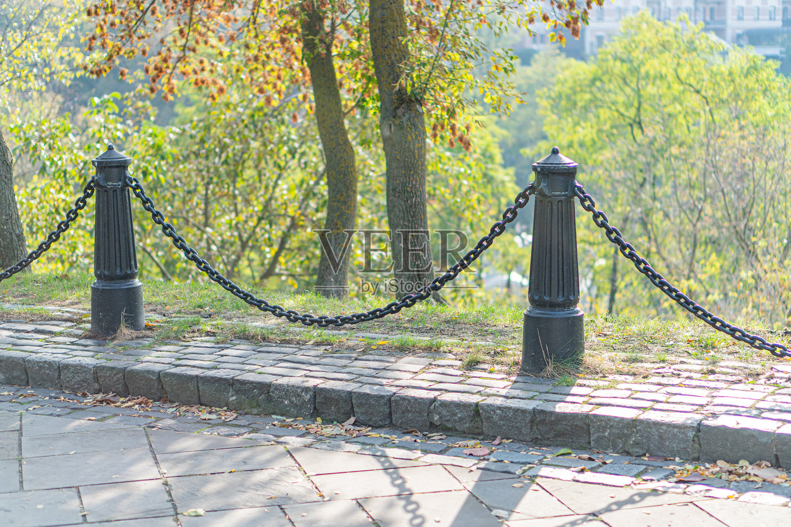 一个迷人而温馨的场景，鹅卵石小径通向一个宁静的湖泊，位于一个维护良好的公园中。透视效果增强了深度，而温暖的色彩和柔和的光线则增添了宁静的氛围。照片摄影图片