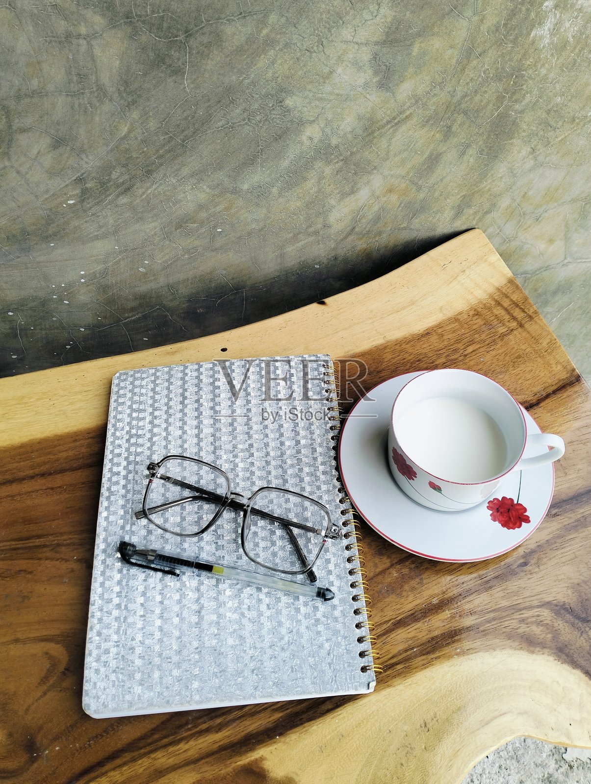 木桌上放着笔记本、钢笔、眼镜和一杯牛奶。照片摄影图片