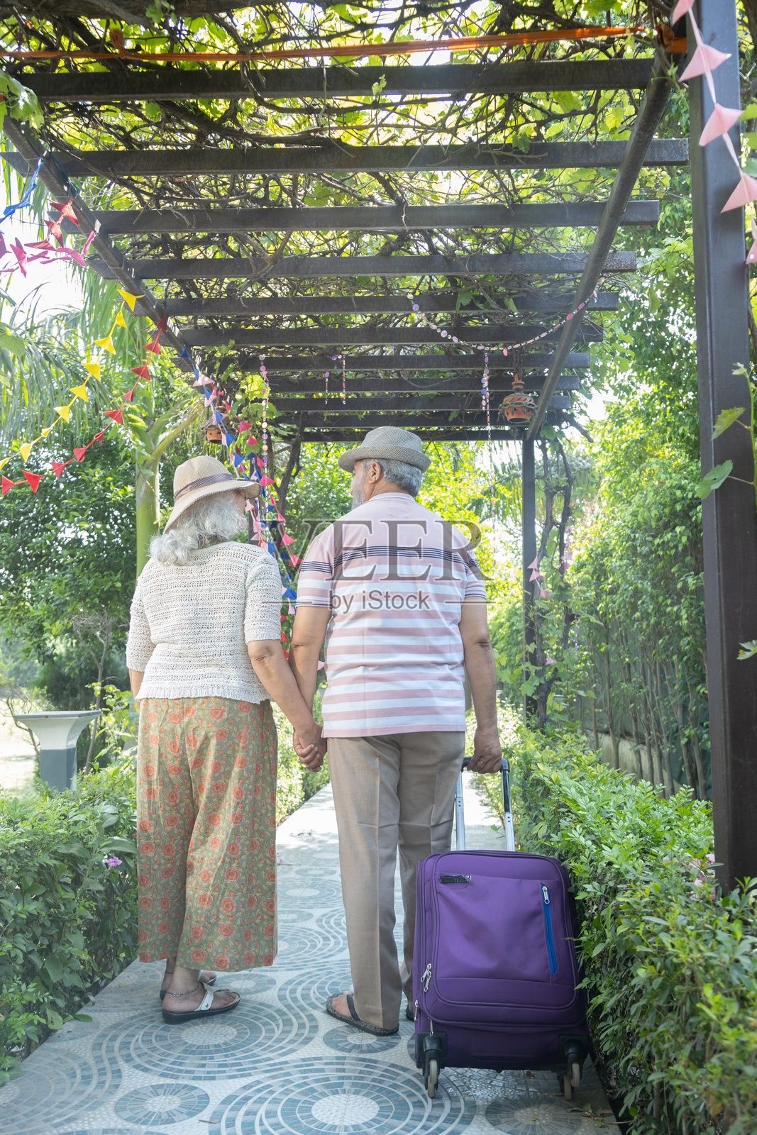 退休的印度旅行夫妇带着行李箱一起享受夏季假期，快乐的成熟夫妻在度假村散步，老年印度游客，退休生活。照片摄影图片
