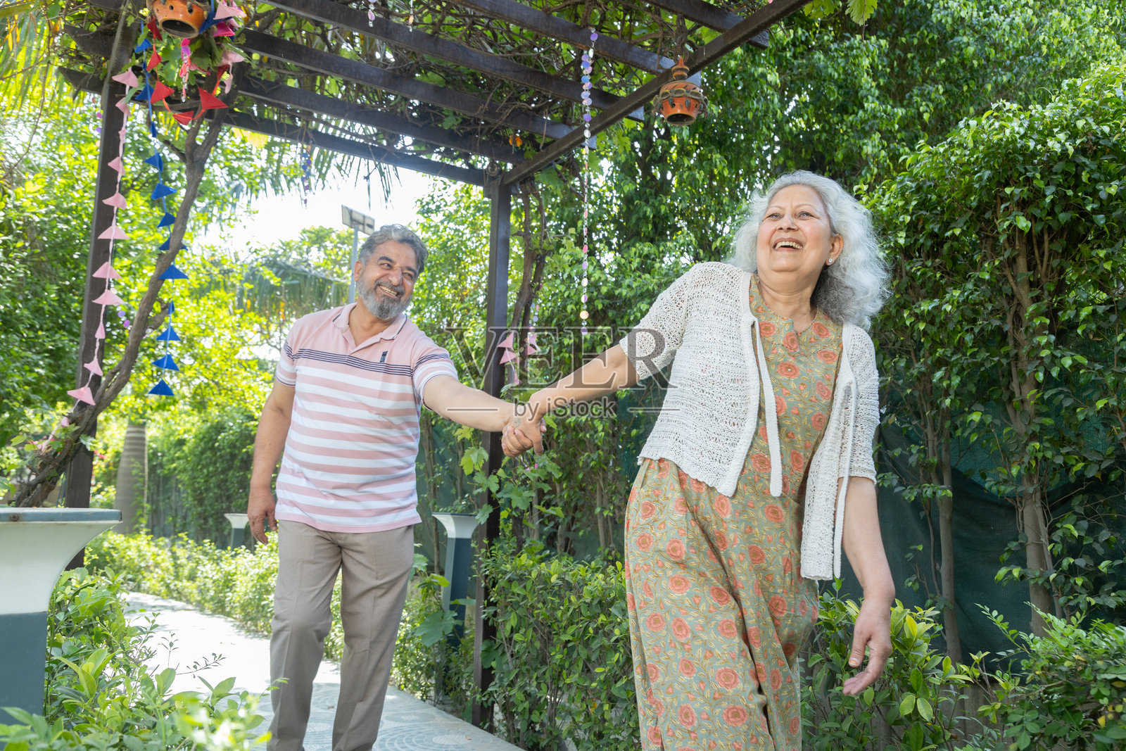 快乐的退休印度老年夫妇手牵手一起散步。成熟的夫妻享受夏季假期。老年人之间的爱与亲密。退休生活。照片摄影图片