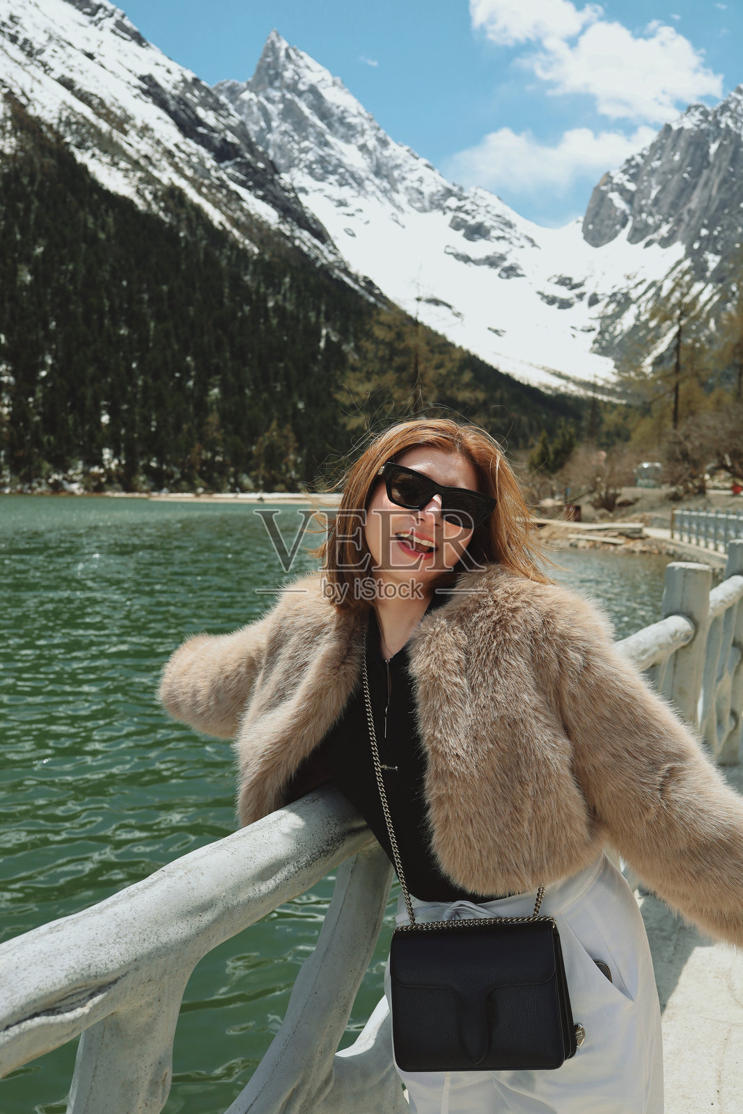 在中国九寨沟，微笑的旅行者与风景如画的湖泊和雪山相伴照片摄影图片