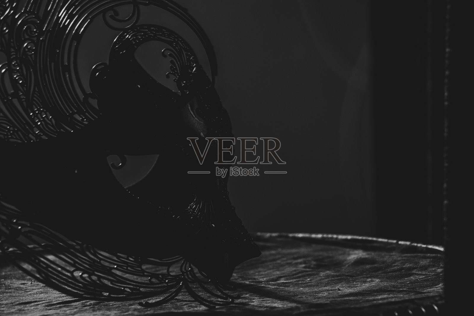 黑暗中，狂欢节面具静静地躺在桌子上，营造出神秘的氛围。照片摄影图片