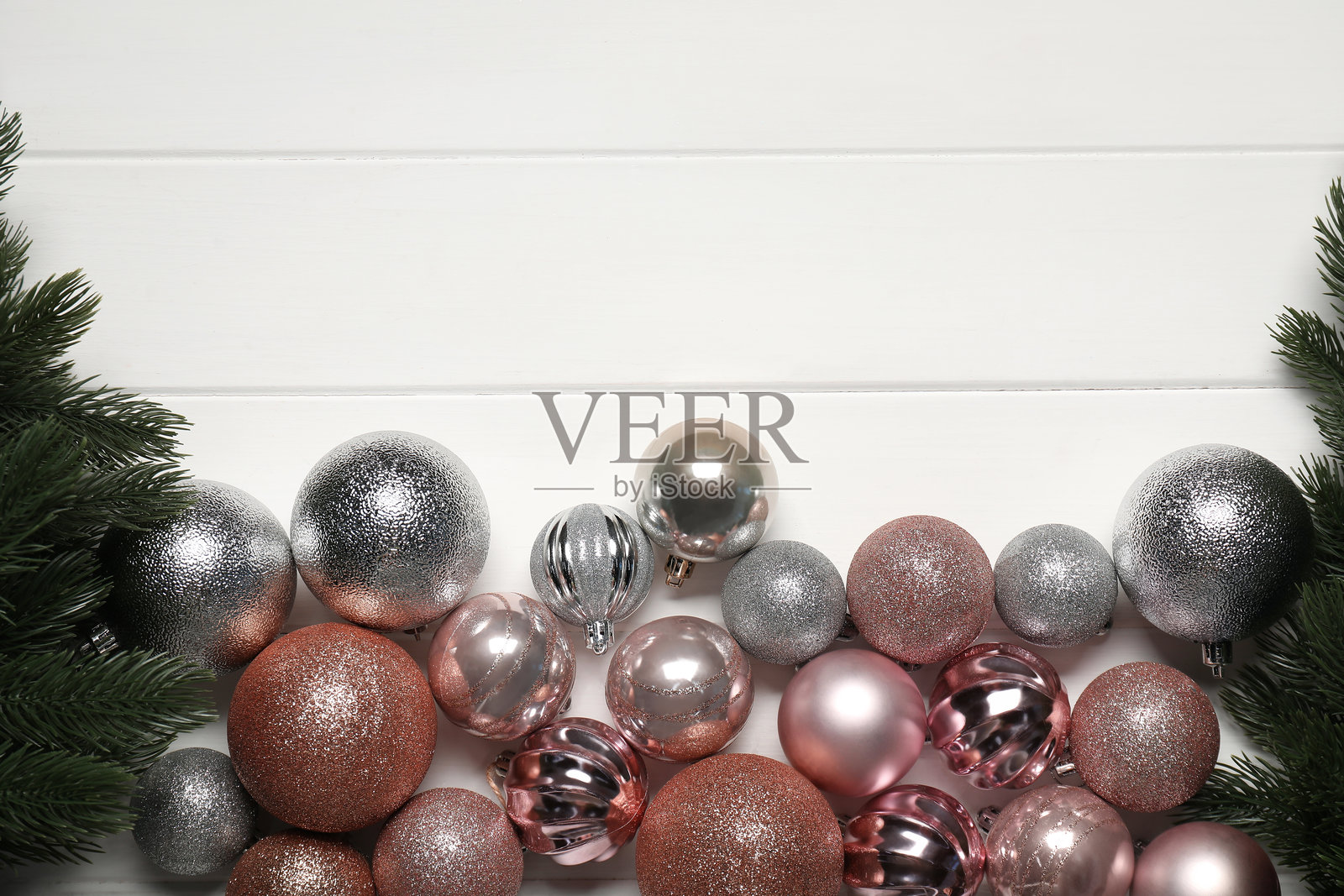 白色木桌上的冷杉树枝和圣诞装饰球，俯视图。留有文字空间。照片摄影图片