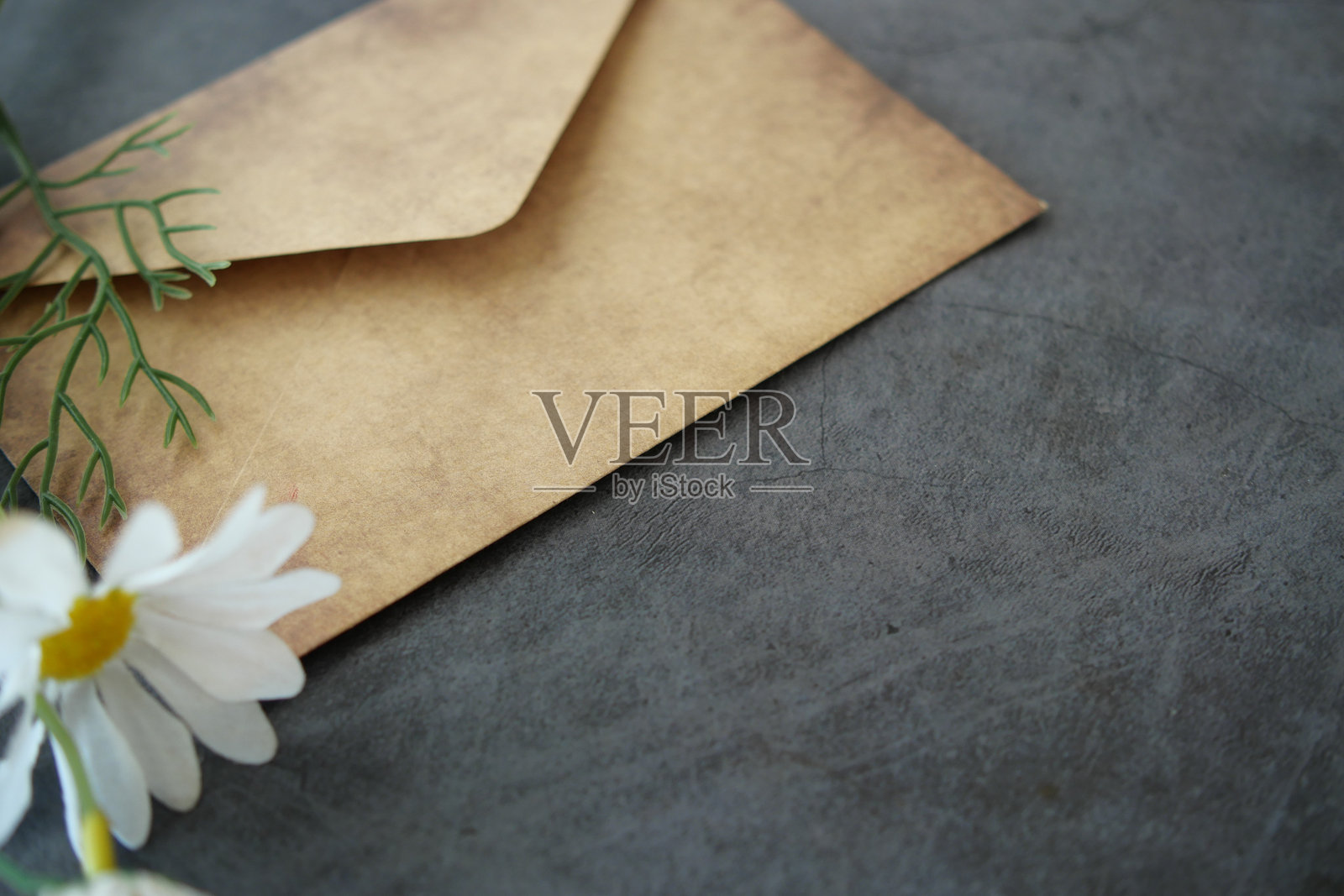 怀旧的信封放在有纹理的表面上，旁边有一朵白花照片摄影图片