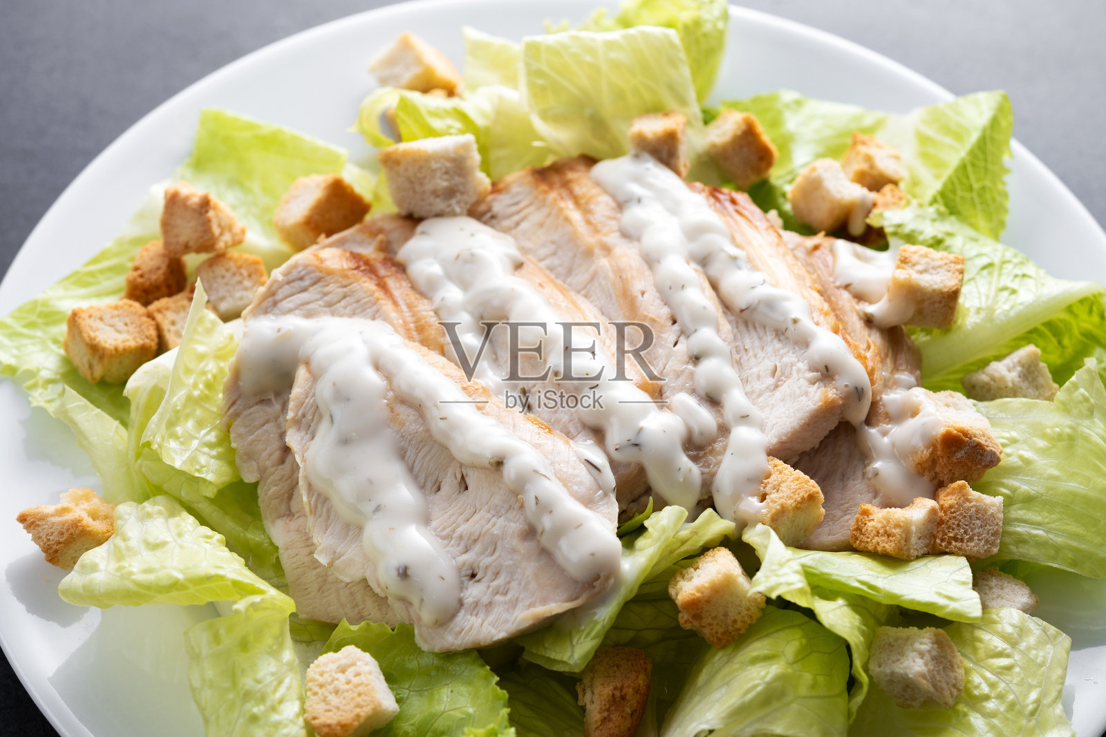 经典凯撒沙拉 新鲜脆口的凯撒沙拉摆放在黑色石板背景上照片摄影图片