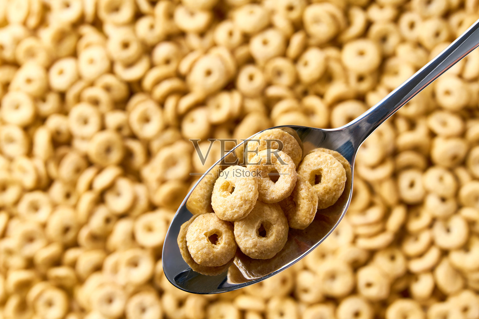 金属勺子里的全谷物麦圈，背景是麦圈。文本留白空间。照片摄影图片