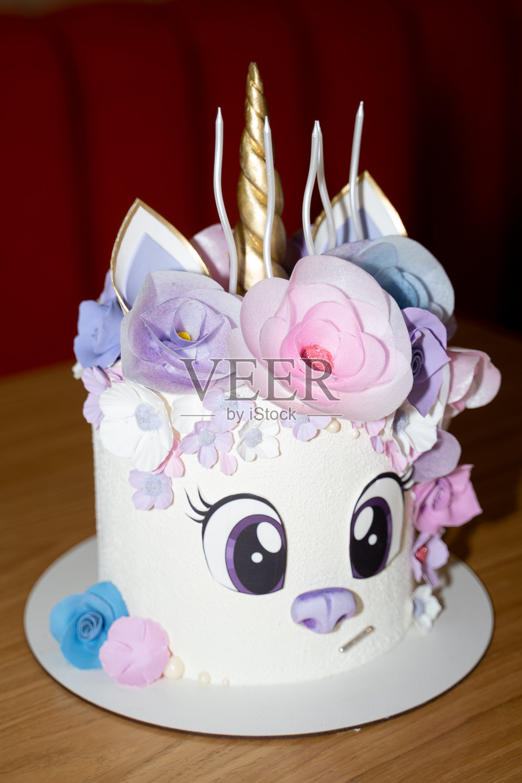 美味的彩虹独角兽蛋糕，配有大眼睛、花卉甜美装饰、金色角和五根蜡烛，适合小女孩的生日许愿。照片摄影图片