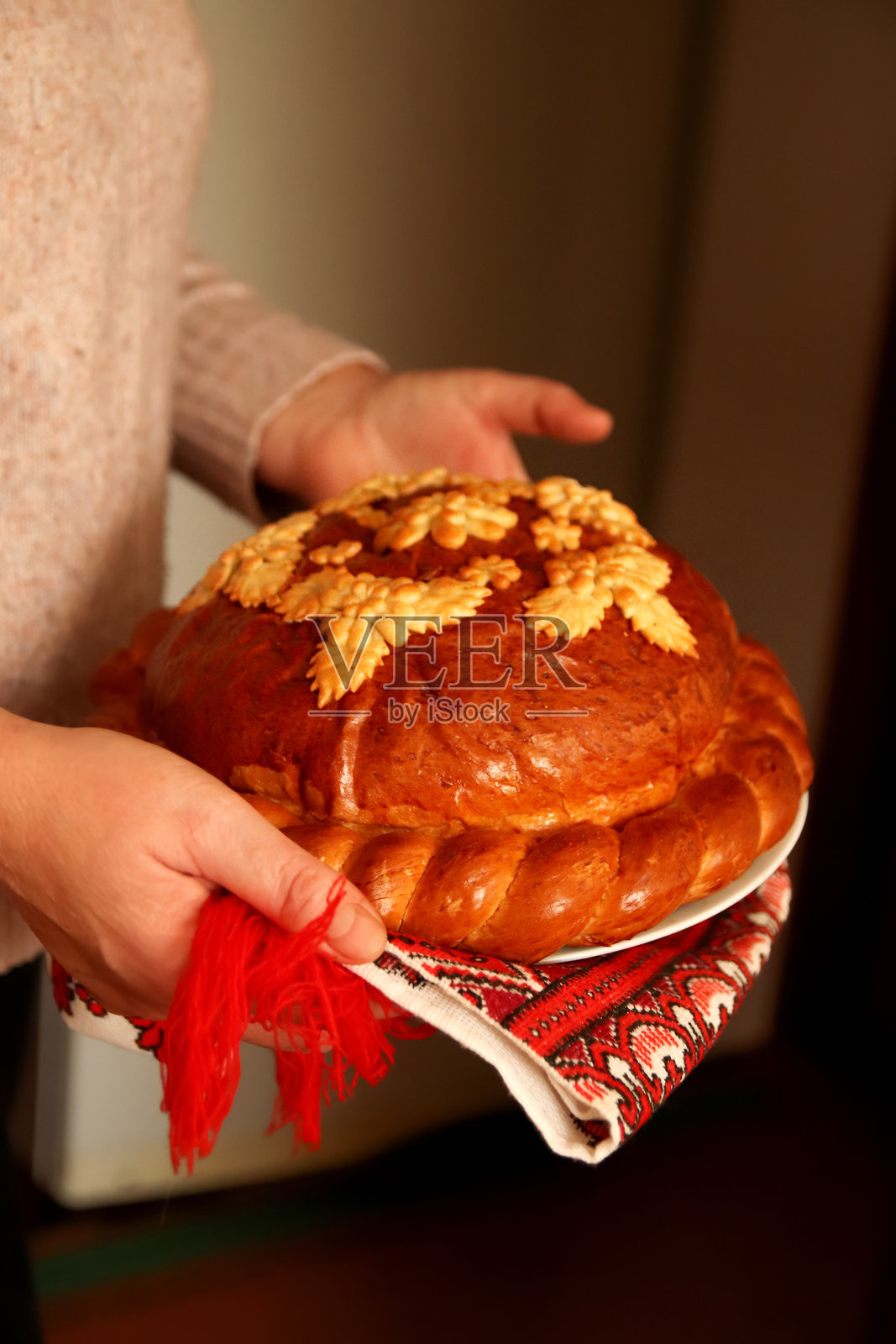 手持传统乌克兰的科罗瓦伊，象征着庆祝和热情好客。这种精美装饰的面包上有复杂的面团图案，通常带有小麦的主题。照片摄影图片