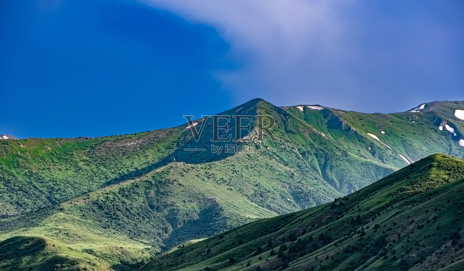 青山上覆盖着雪的山峰，映衬在明亮的蓝天之下。照片摄影图片