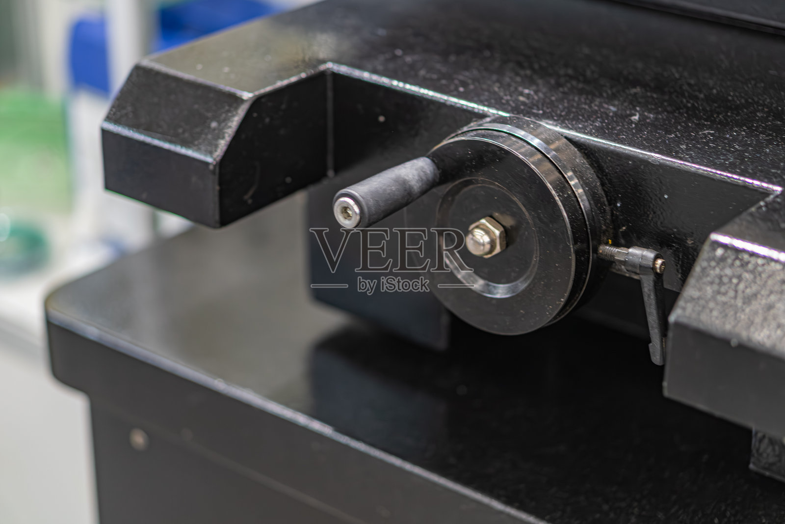 一个车间或实验室环境中，蓝色工作台上有一个机械组件。中央物体是一个带螺栓的圆形金属部件，可能是工业设备或精密仪器的一部分。照片摄影图片