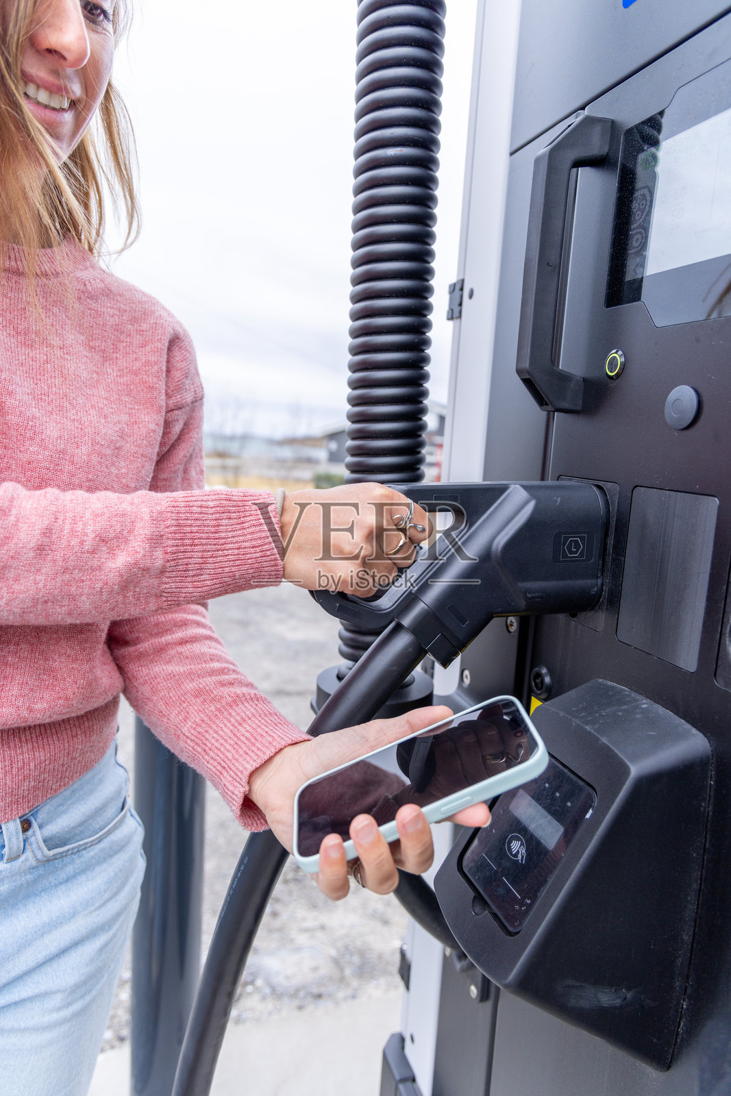 女性在电动车充电站使用NFC支付照片摄影图片