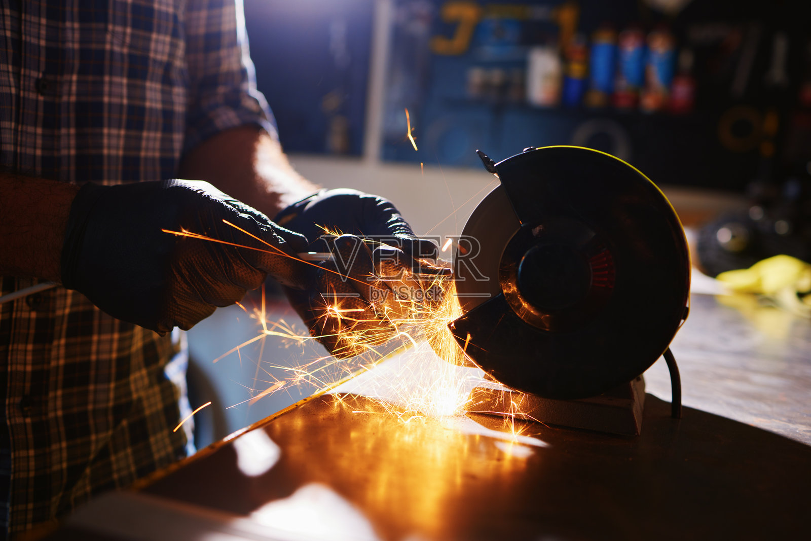 机械师在车间用台式磨床磨锐金属部件，产生火花照片摄影图片