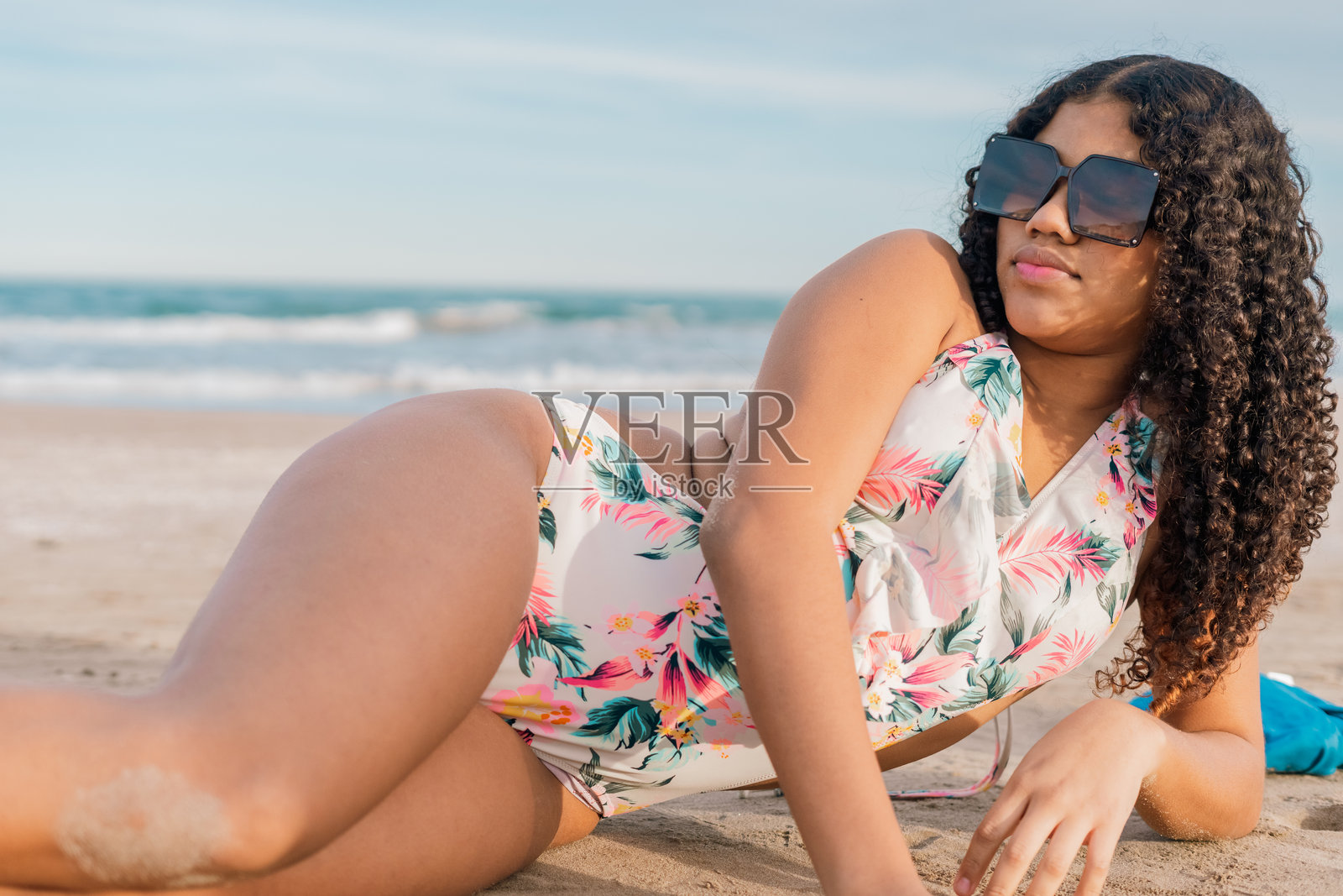 年轻女性在沙滩上放松，佩戴着太阳镜照片摄影图片