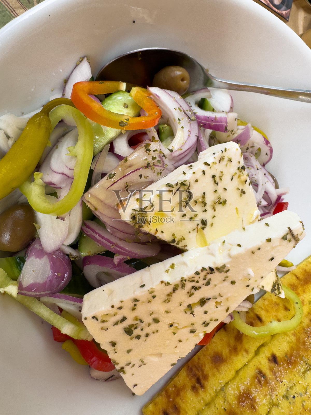 希腊沙拉，配有橄榄、黄瓜、洋葱和羊奶酪，竖排展示照片摄影图片