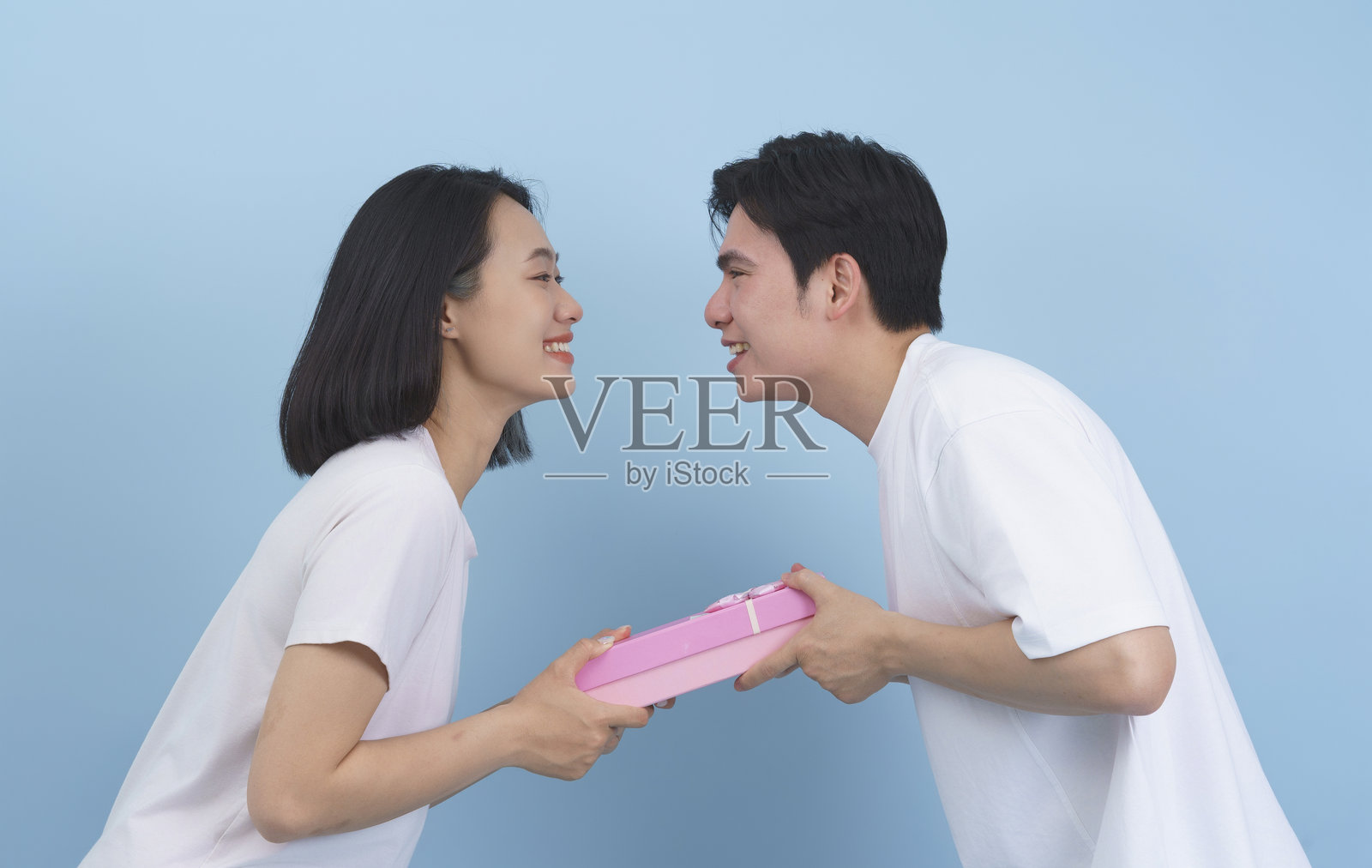 友好的情侣微笑着在蓝色背景下互赠礼物照片摄影图片