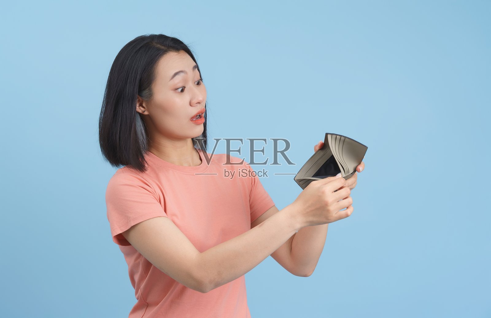 担忧的女人看着空钱包，背景简单照片摄影图片