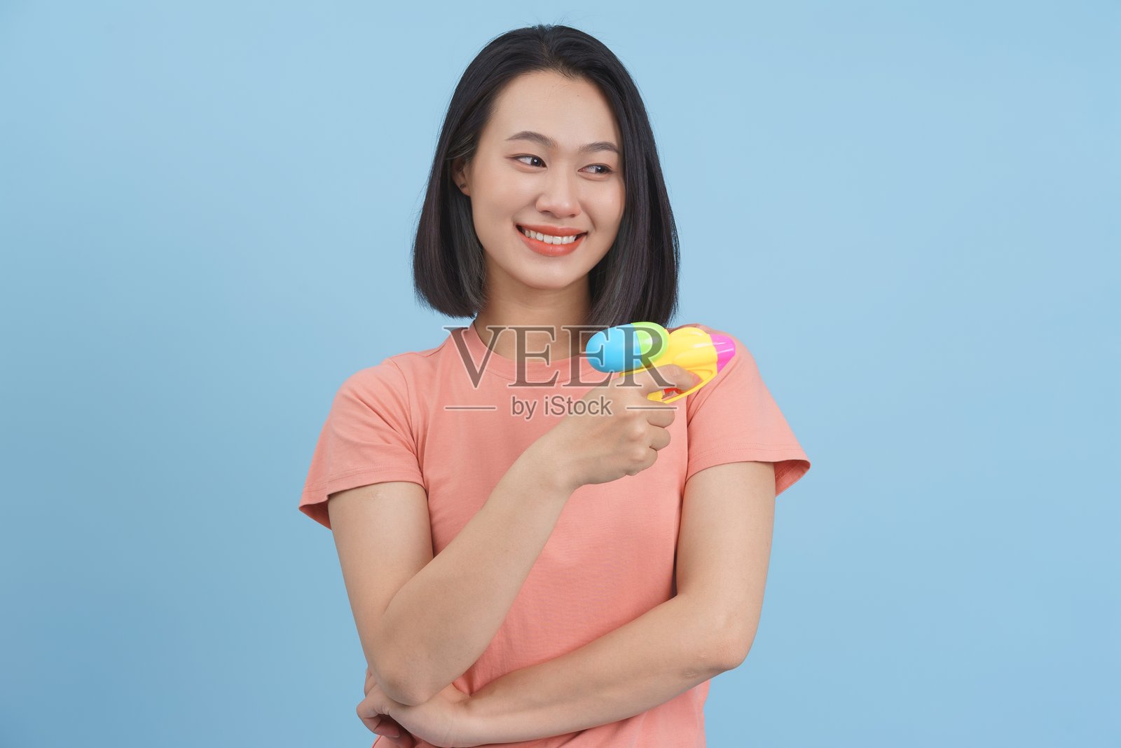 微笑的女性手持五彩水玩具，背景为蓝色照片摄影图片