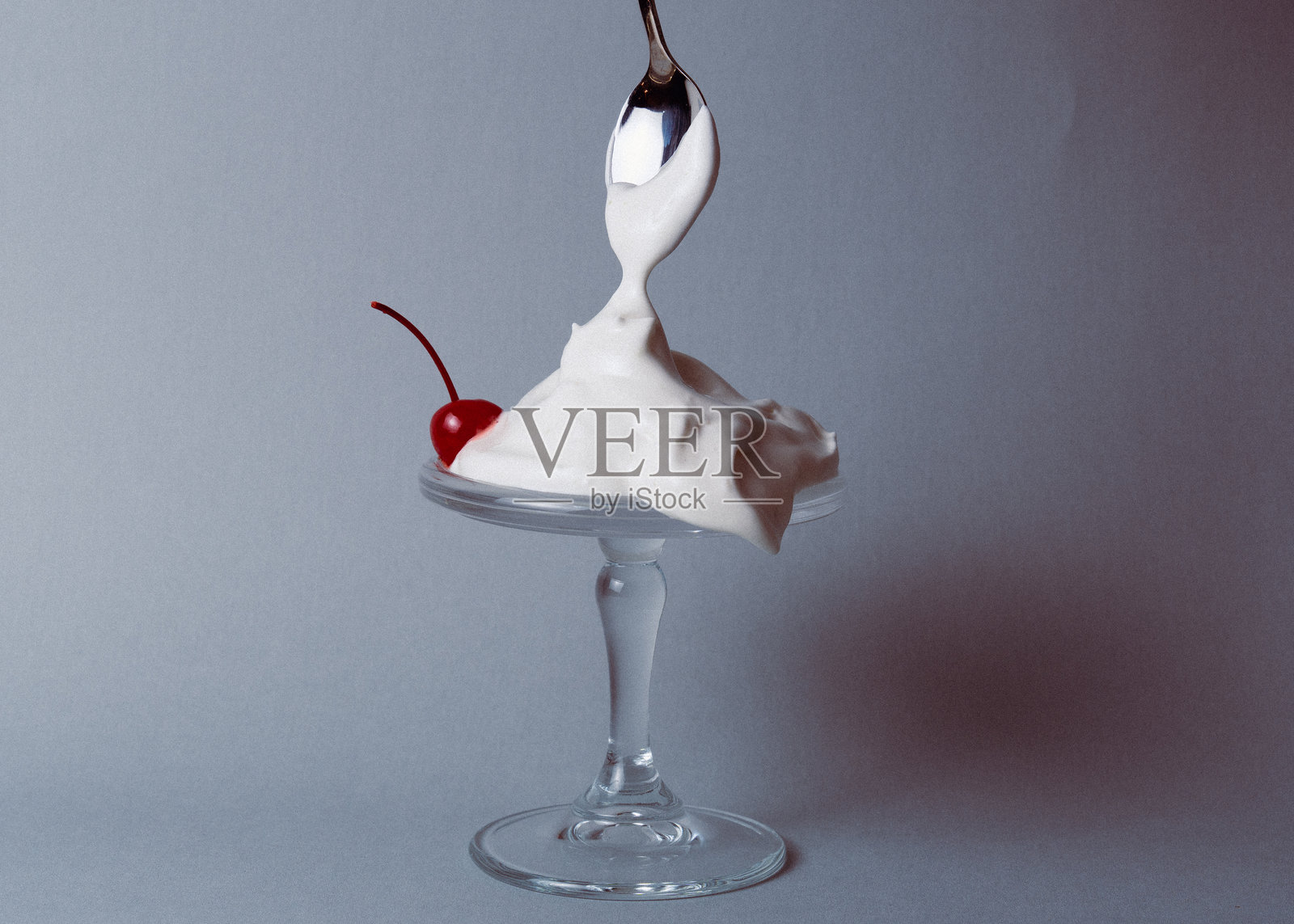 勺子在奶油甜点上淋上奶油，配有樱桃照片摄影图片