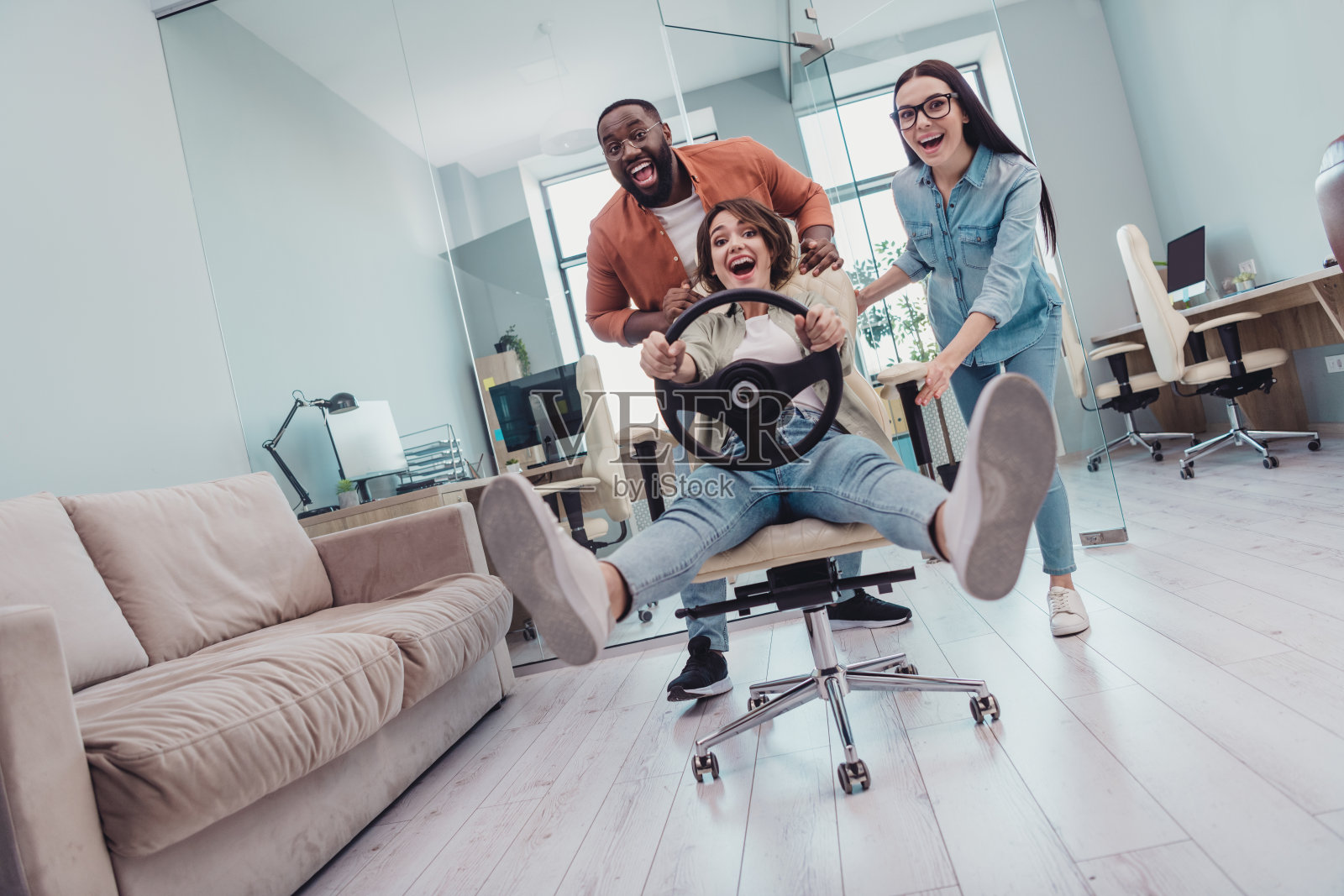 现代工作空间中，积极的女CEO和男市场营销人员放松休息，玩网络科技竞速游戏的全身照片。照片摄影图片