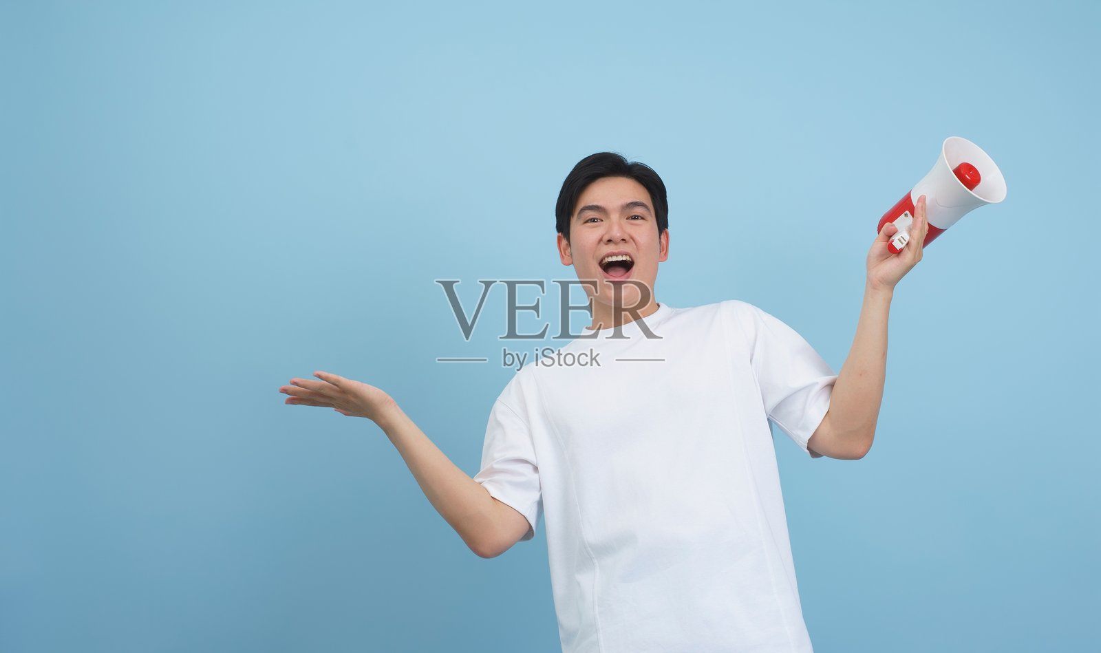 快乐的男人举起手臂，手持扩音器，背景为蓝色照片摄影图片