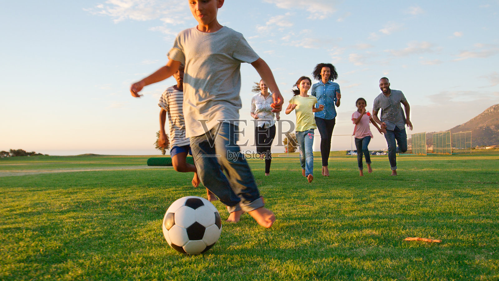 多元文化家庭在公园里享受傍晚的阳光踢足球照片摄影图片