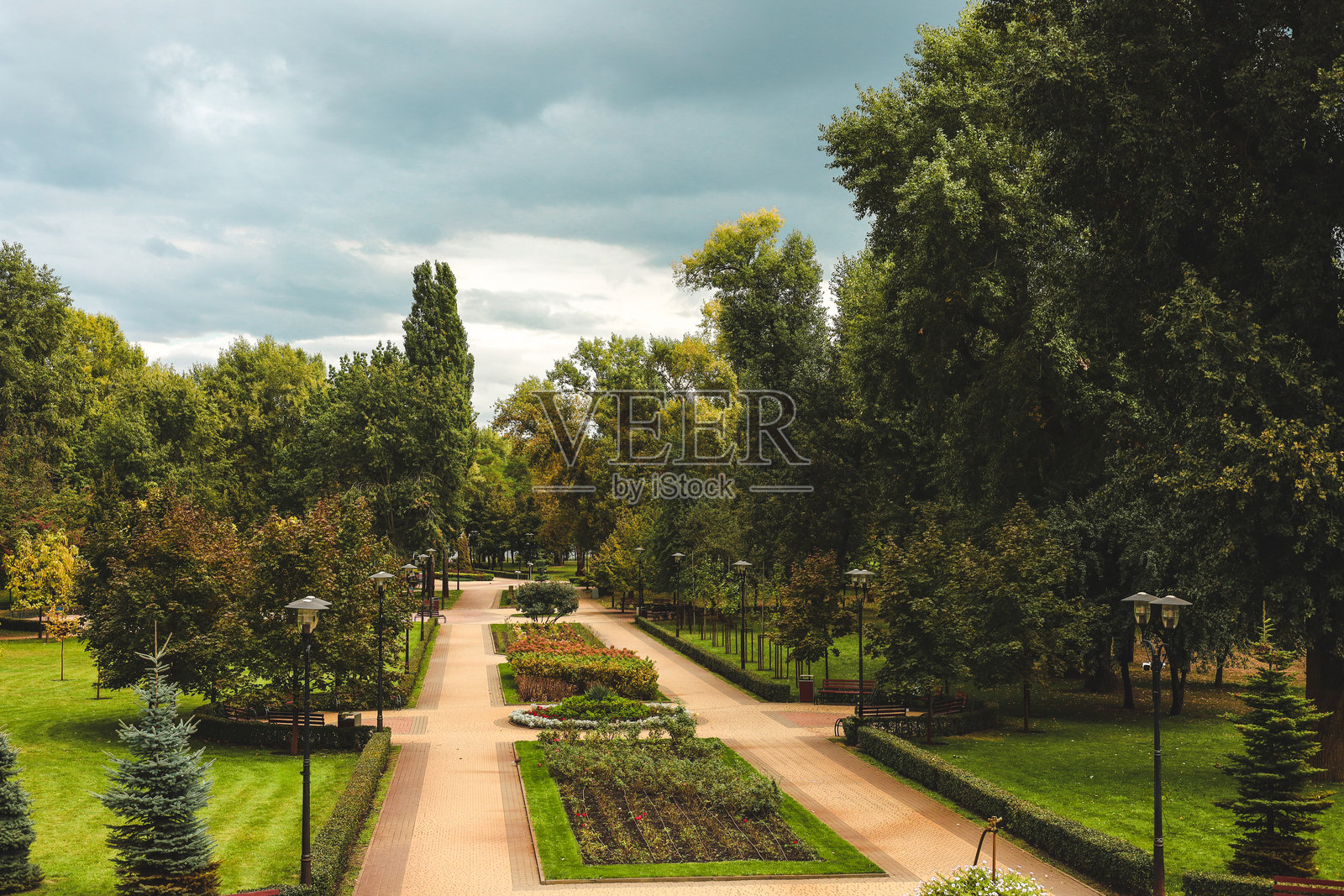 城市公园中，阴天的宁静步道两旁种满了树木和花卉照片摄影图片