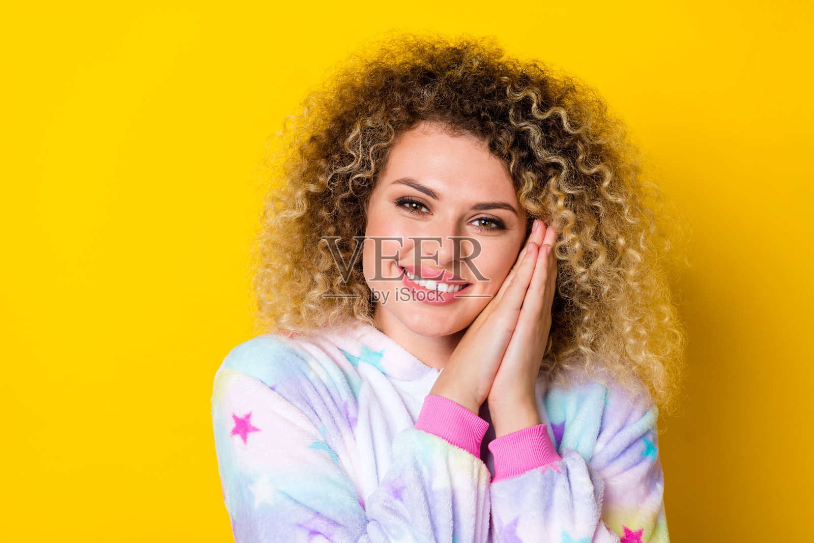 穿着睡衣的迷人、快乐、甜美的波浪卷发女孩在明亮的黄色背景下懒洋洋地放松。照片摄影图片