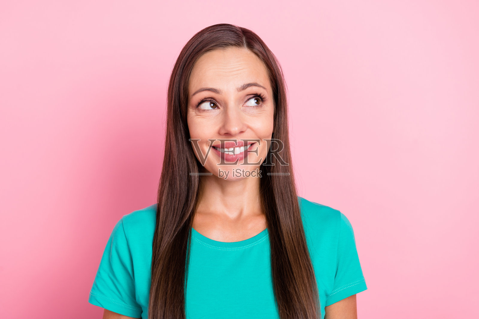 梦幻灵感的女士凝视空旷空间，脑海中充满创意思绪，穿着青绿色T恤，背景为粉色。照片摄影图片