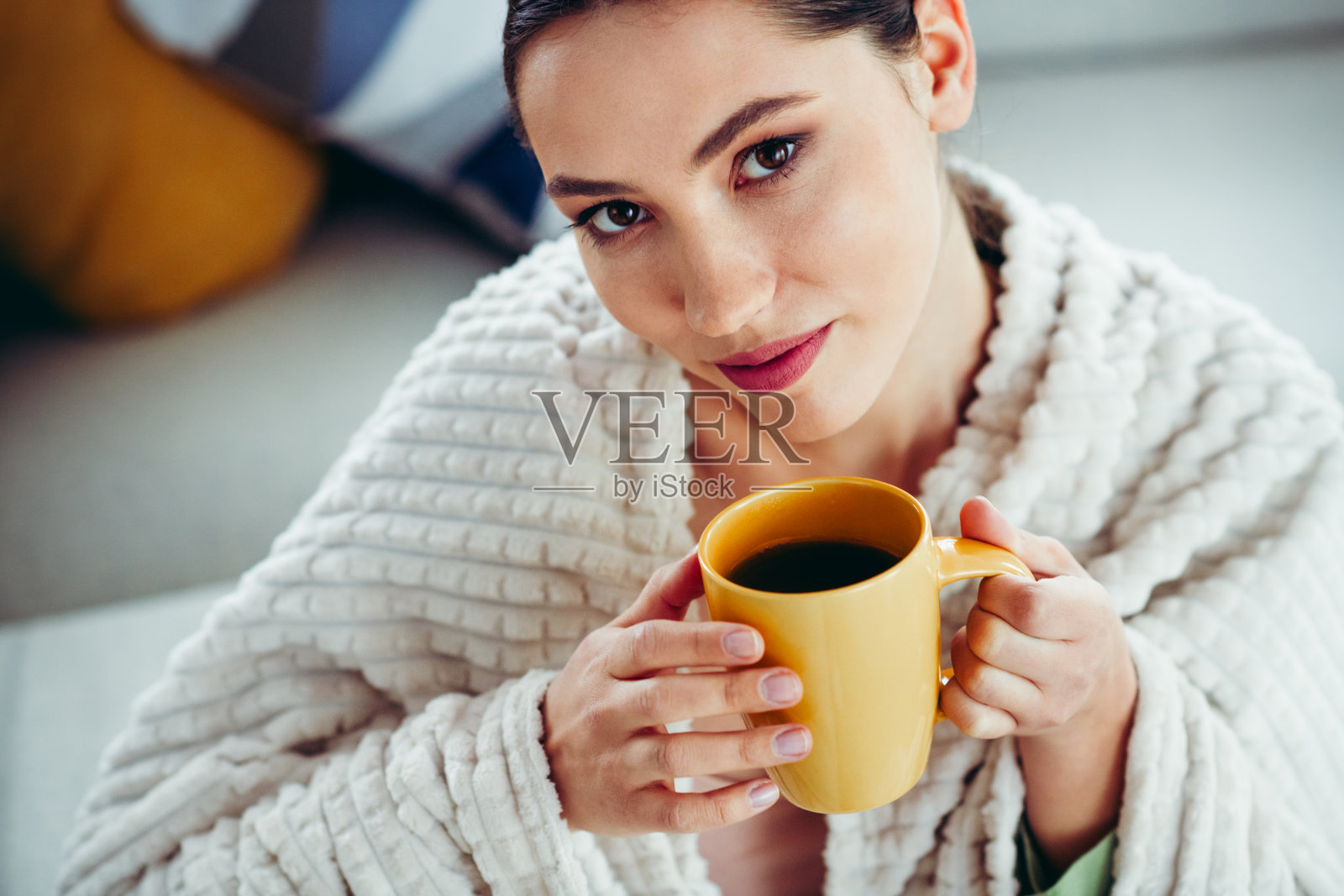可爱的女性在家中享受温暖的饮品，裹着舒适的浴袍，面露宁静与舒适的表情照片摄影图片