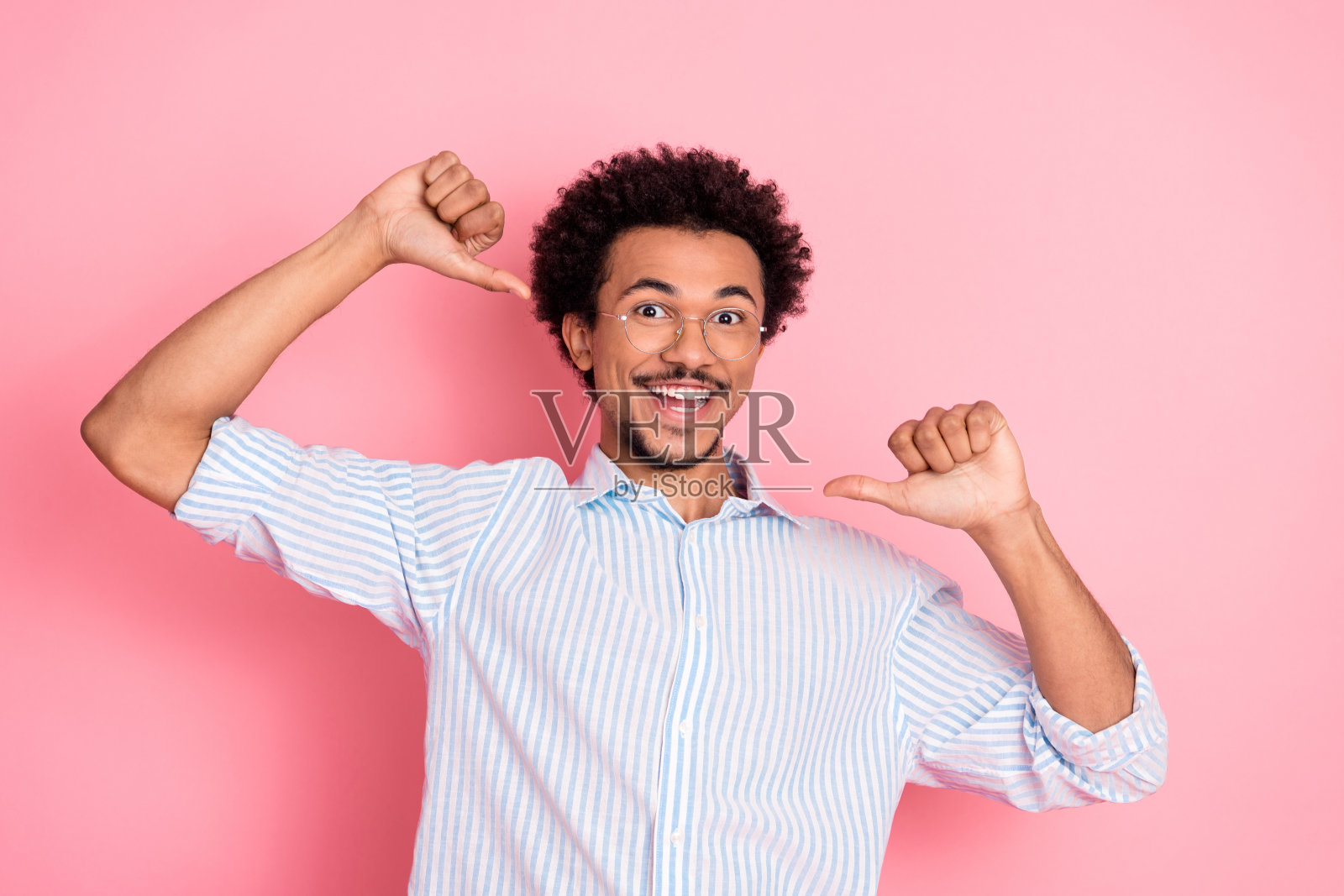兴奋的年轻男子在充满活力的粉色背景前，自信地做手势，展现出快乐的情绪。照片摄影图片