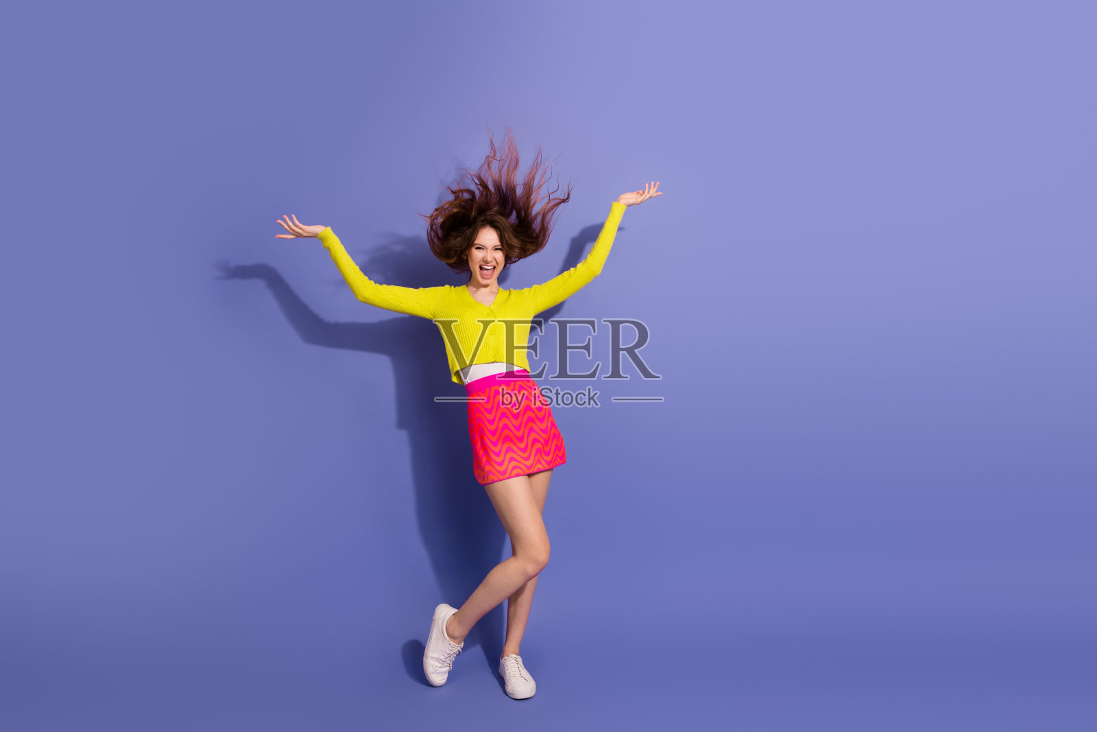 充满活力的年轻女性穿着鲜艳的服装，在紫色背景下享受闲暇时光照片摄影图片