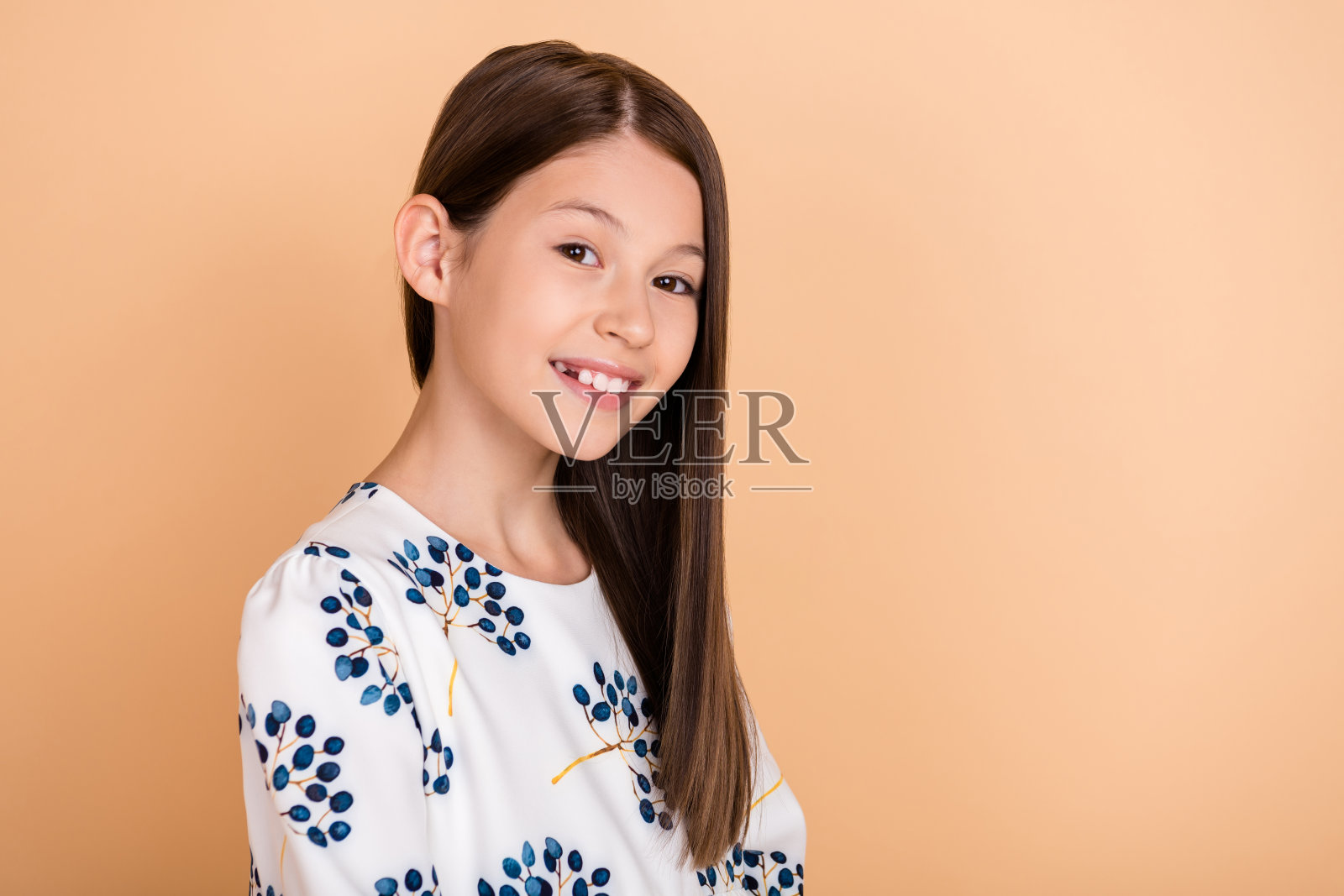 棕发迷人女孩的侧面肖像，愉快而有吸引力，背景为米色柔和色调，留有空白空间。照片摄影图片