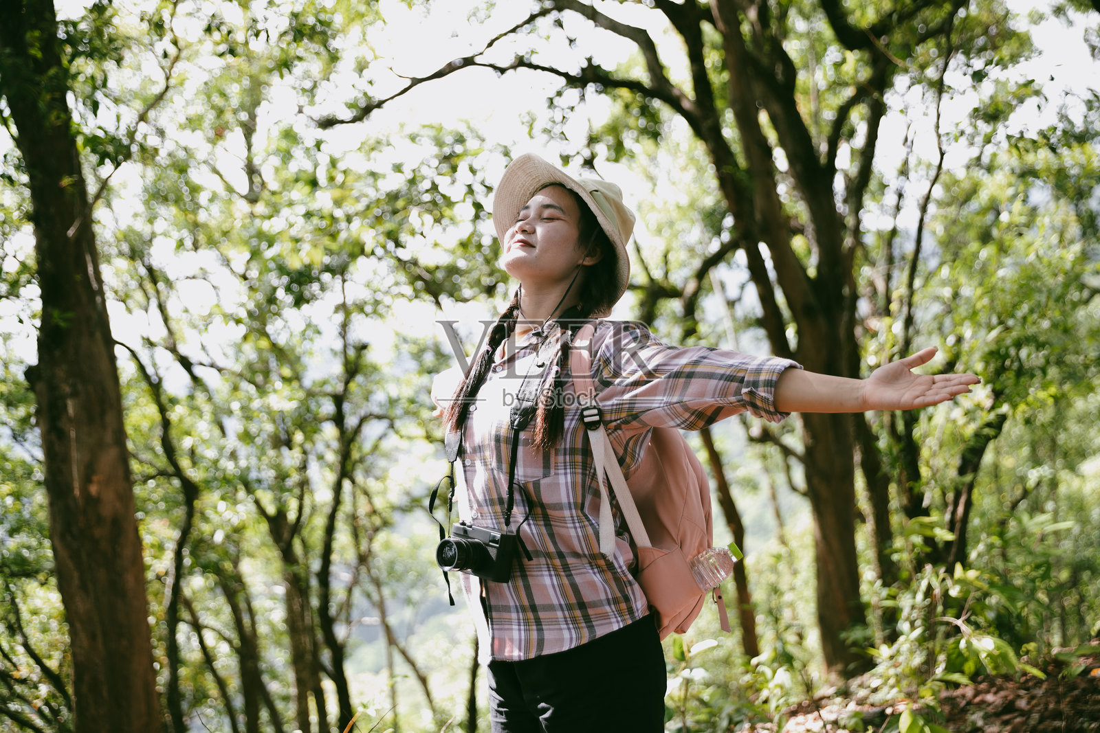 年轻女性背着背包在国家公园或森林中行走。自然中的休闲运动。女性背包，挥手迎接徒步旅行的旅程。森林探险。背包徒步旅行。照片摄影图片