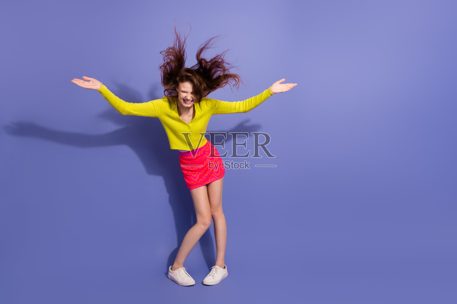 穿着鲜艳时尚服装的年轻女性在紫色背景下开心地玩耍照片摄影图片