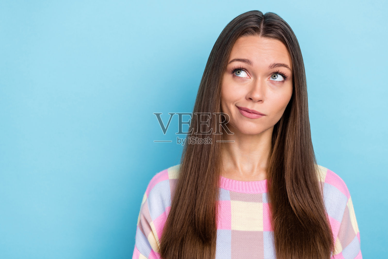 梦幻般的女士凝视空旷的空间，思考约会策略，穿着休闲服，背景为蓝色。照片摄影图片