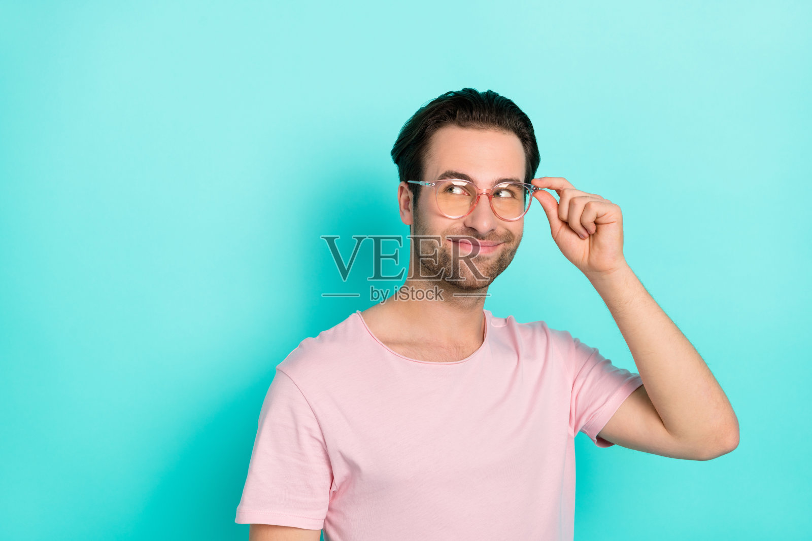 年轻快乐的男士，面带思索的梦幻表情，独自站在青绿色背景前。照片摄影图片