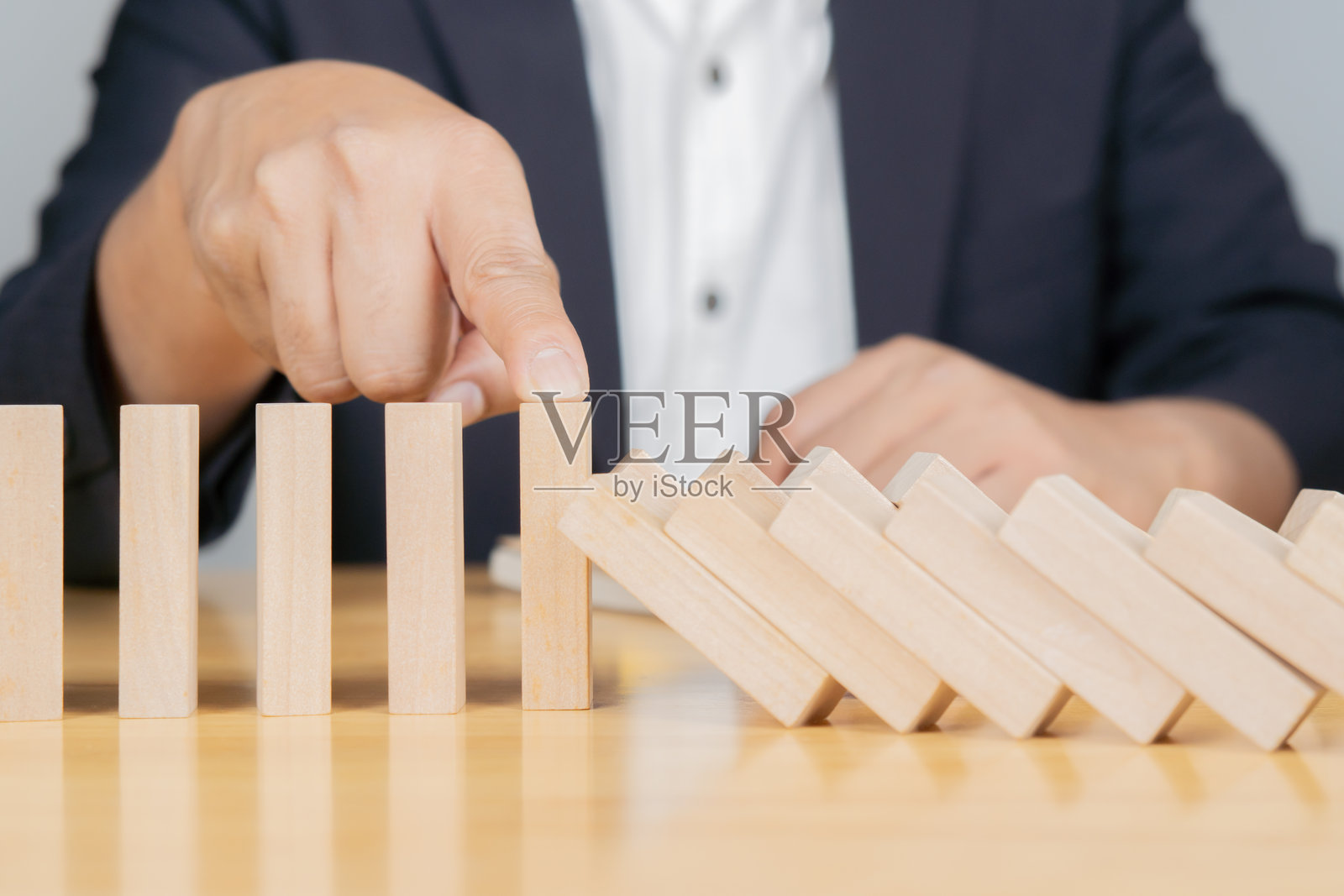 安全商业发展概念。商人用手阻止桌子上掉落的积木。照片摄影图片