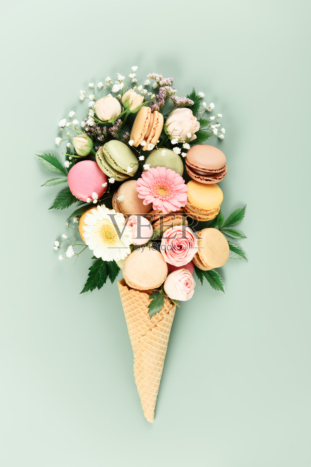 粉色绿背景上的花卉和马卡龙冰淇淋甜筒照片摄影图片