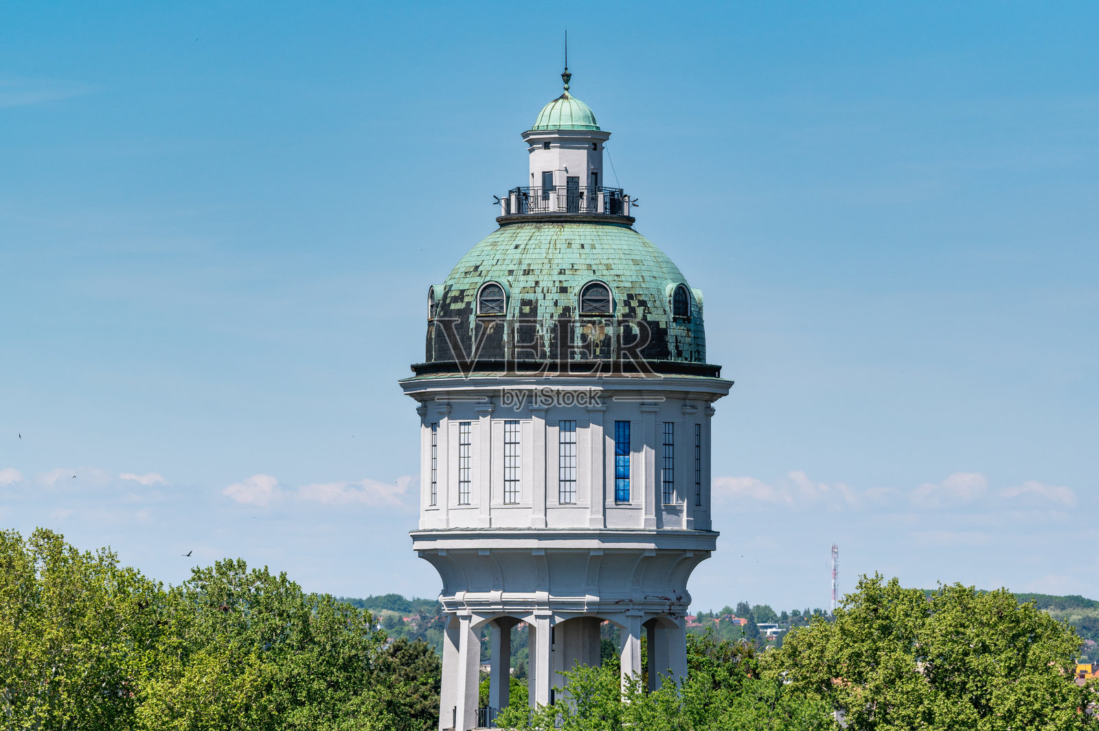 历史悠久的水塔,树梢上方有着铜绿的圆顶照片摄影图片