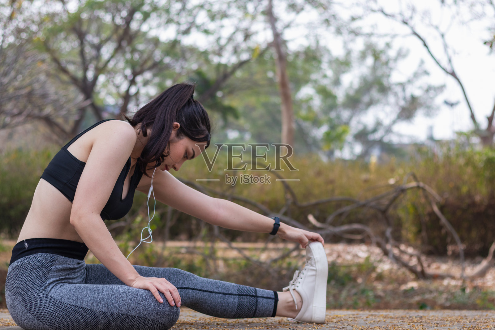 美丽的亚洲女性在热身，准备她的肌肉以减少跑步时的肌肉损伤。美丽的亚洲女性在拉伸肌肉，为跑步做准备。照片摄影图片