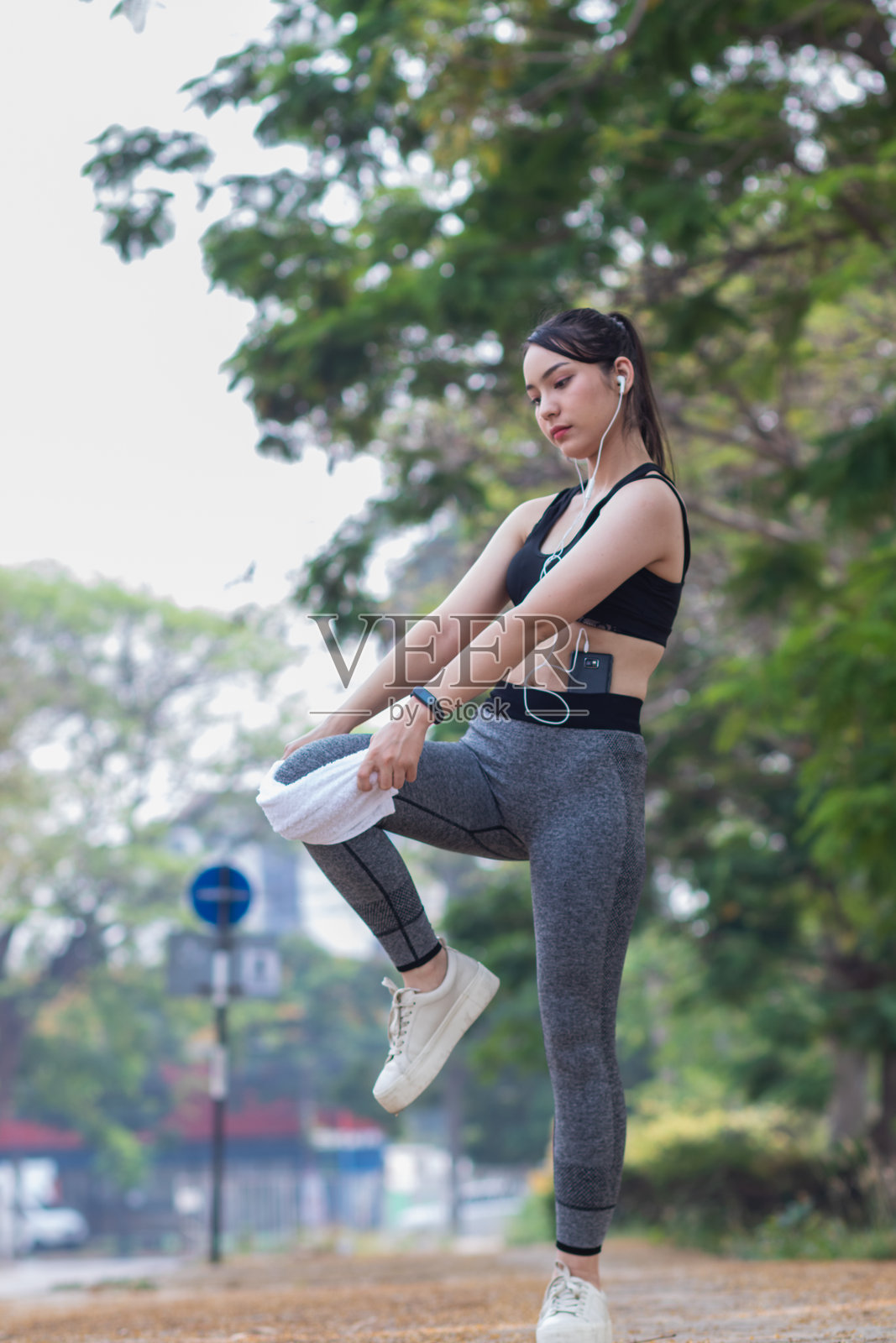 美丽的亚洲女性在热身，准备肌肉以减少跑步时的肌肉损伤。美丽的亚洲女性在拉伸肌肉，为跑步做准备。照片摄影图片