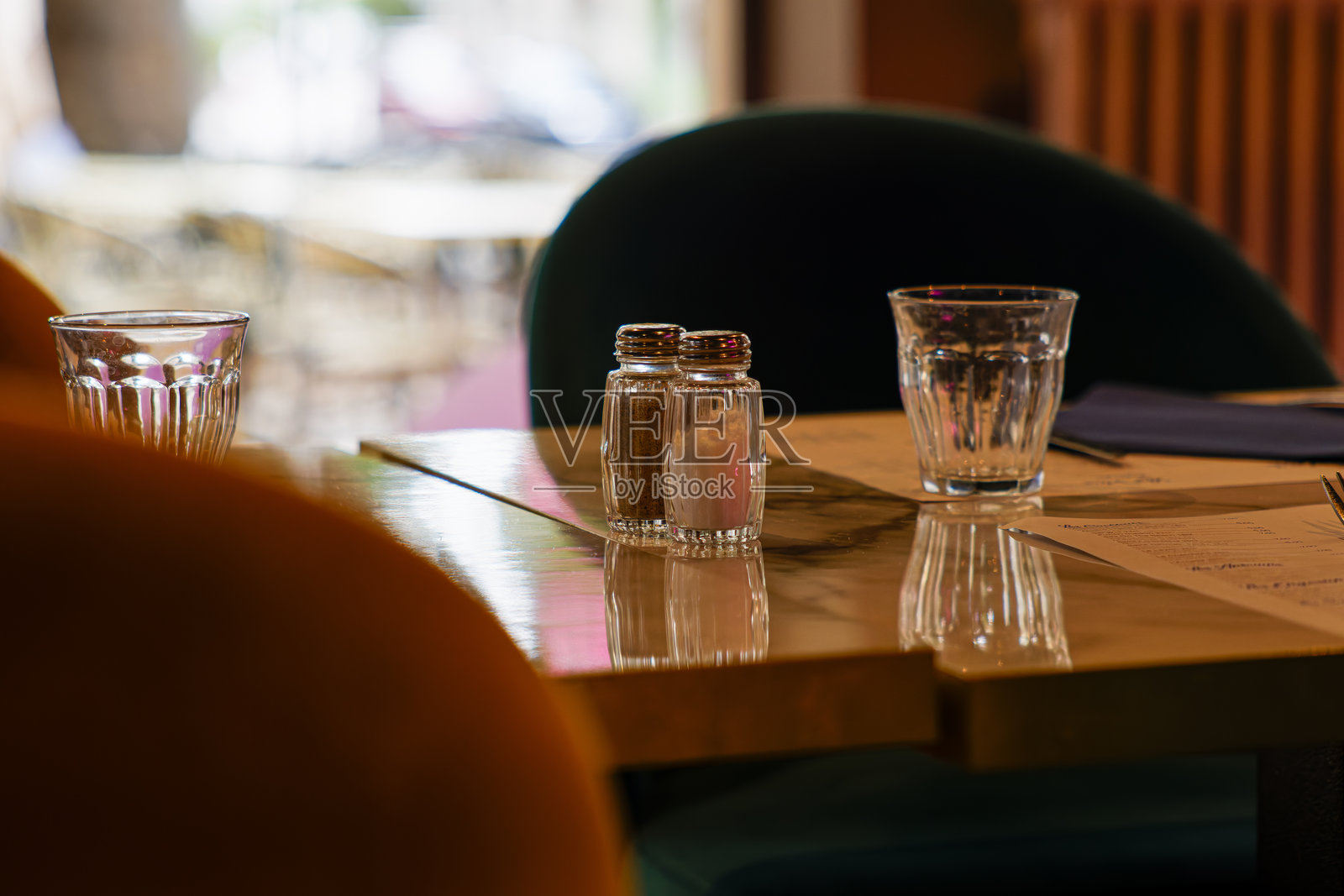 舒适的咖啡馆桌子，上面有盐和胡椒瓶、玻璃杯和菜单。照片摄影图片