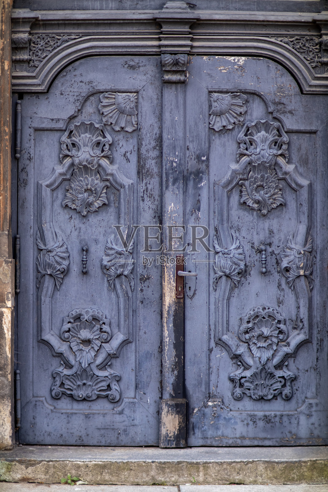 古董蓝色木门，装饰有精美的雕刻花卉图案，漆面剥落。照片摄影图片