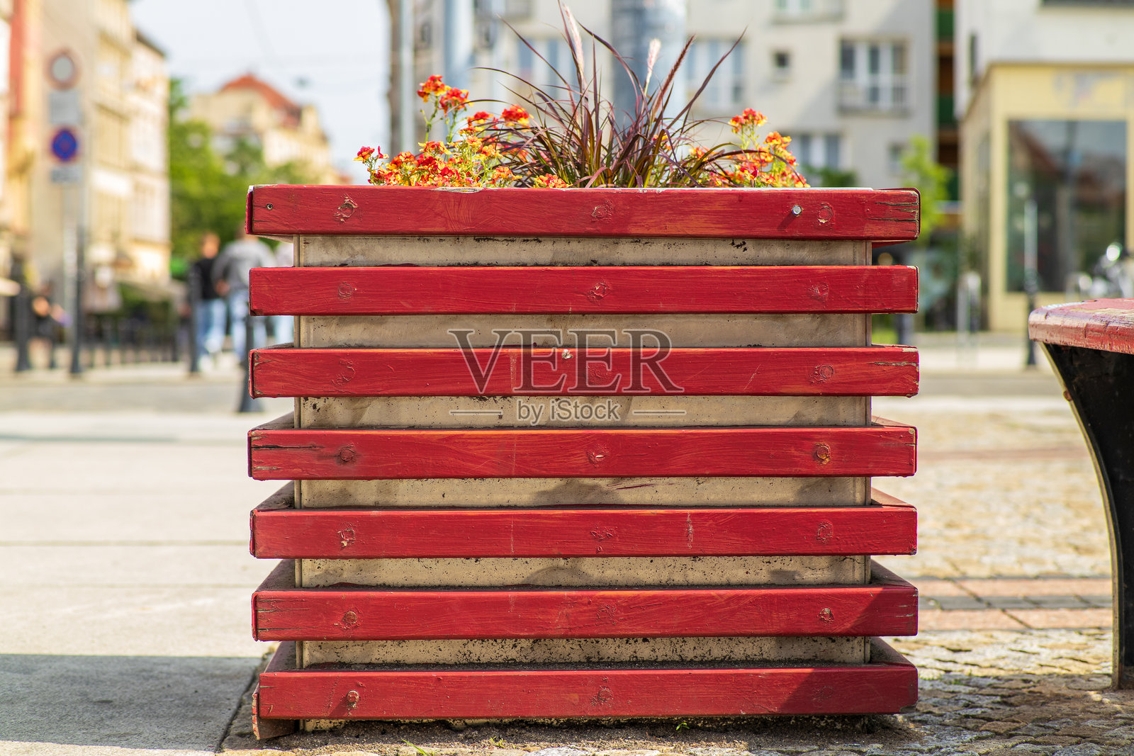 红色木质花盆，盛开着鲜艳的橙色和紫色花朵，位于城市街道上。照片摄影图片